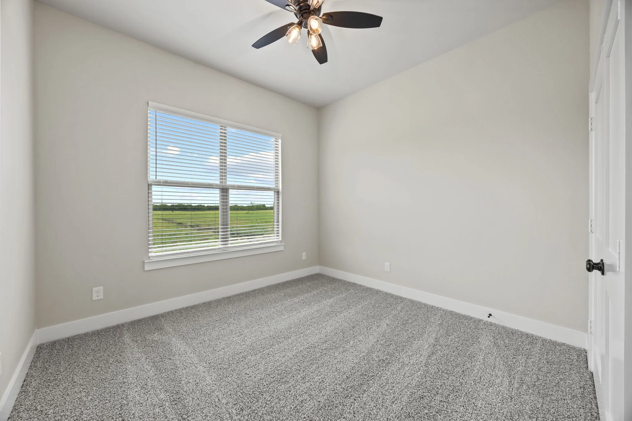 Neutral-toned walls, textured gray carpet, and a multi-pane window with white blinds