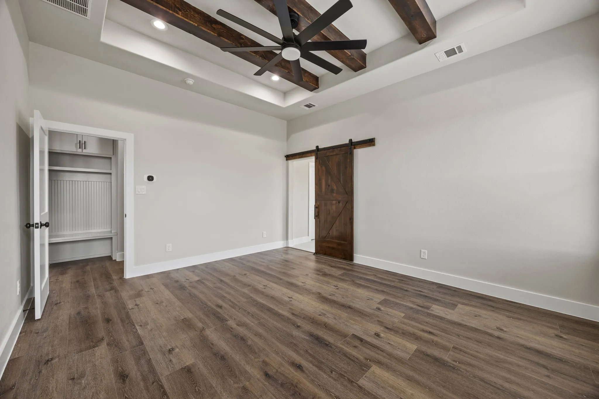 Tray ceiling with wood-beam accents and recessed lighting