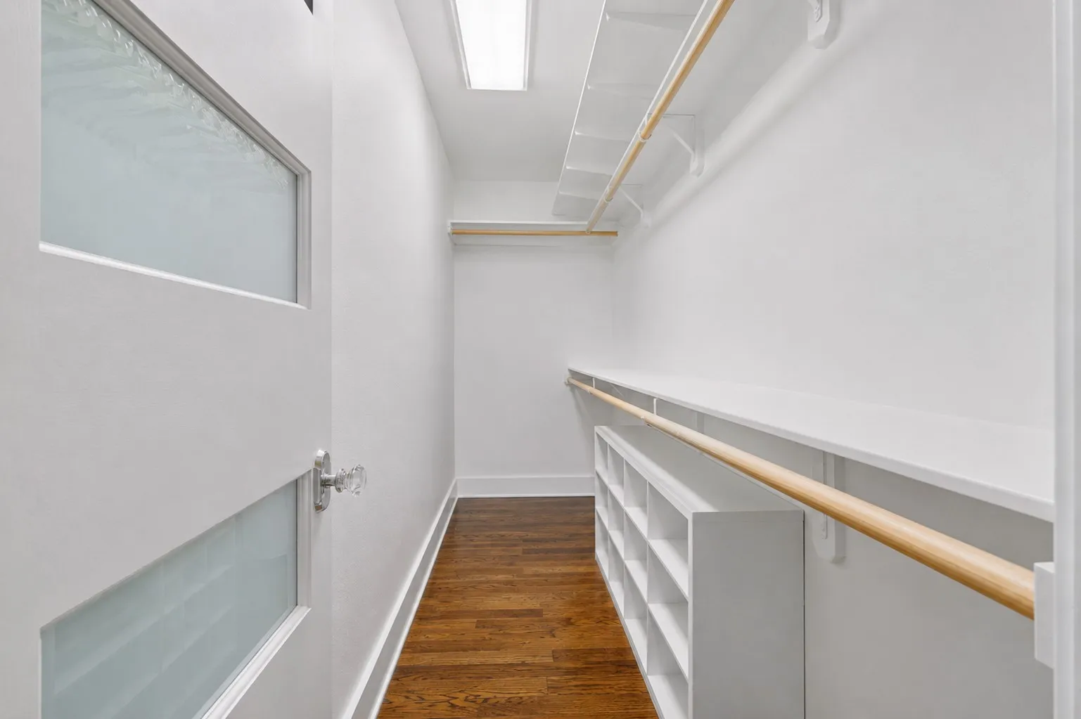Walk-in closet featuring wood-finish flooring, built-in shelving, and hanging rods