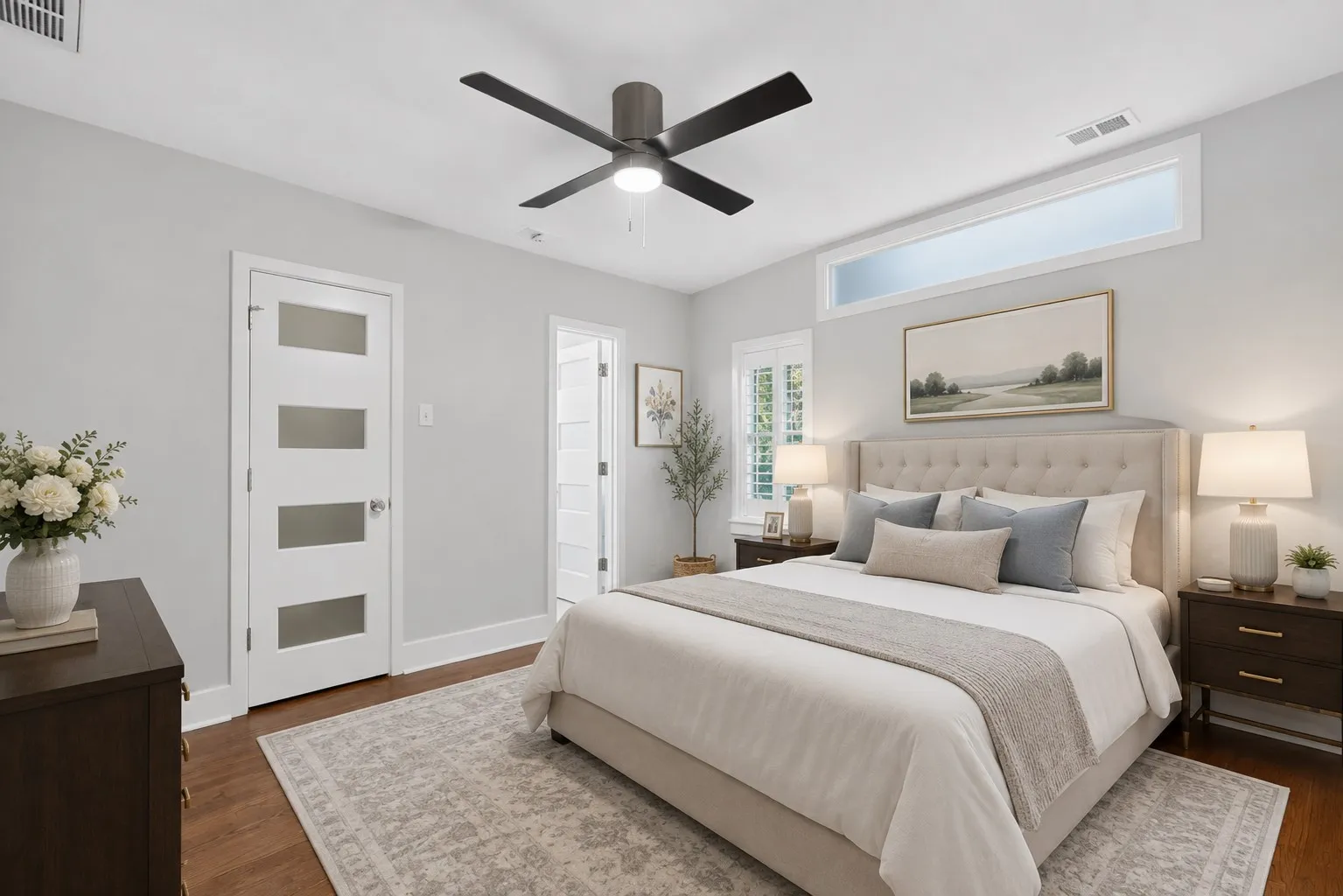 Wood-finish flooring, ceiling fan, transom window, and white interior door with frosted glass panels