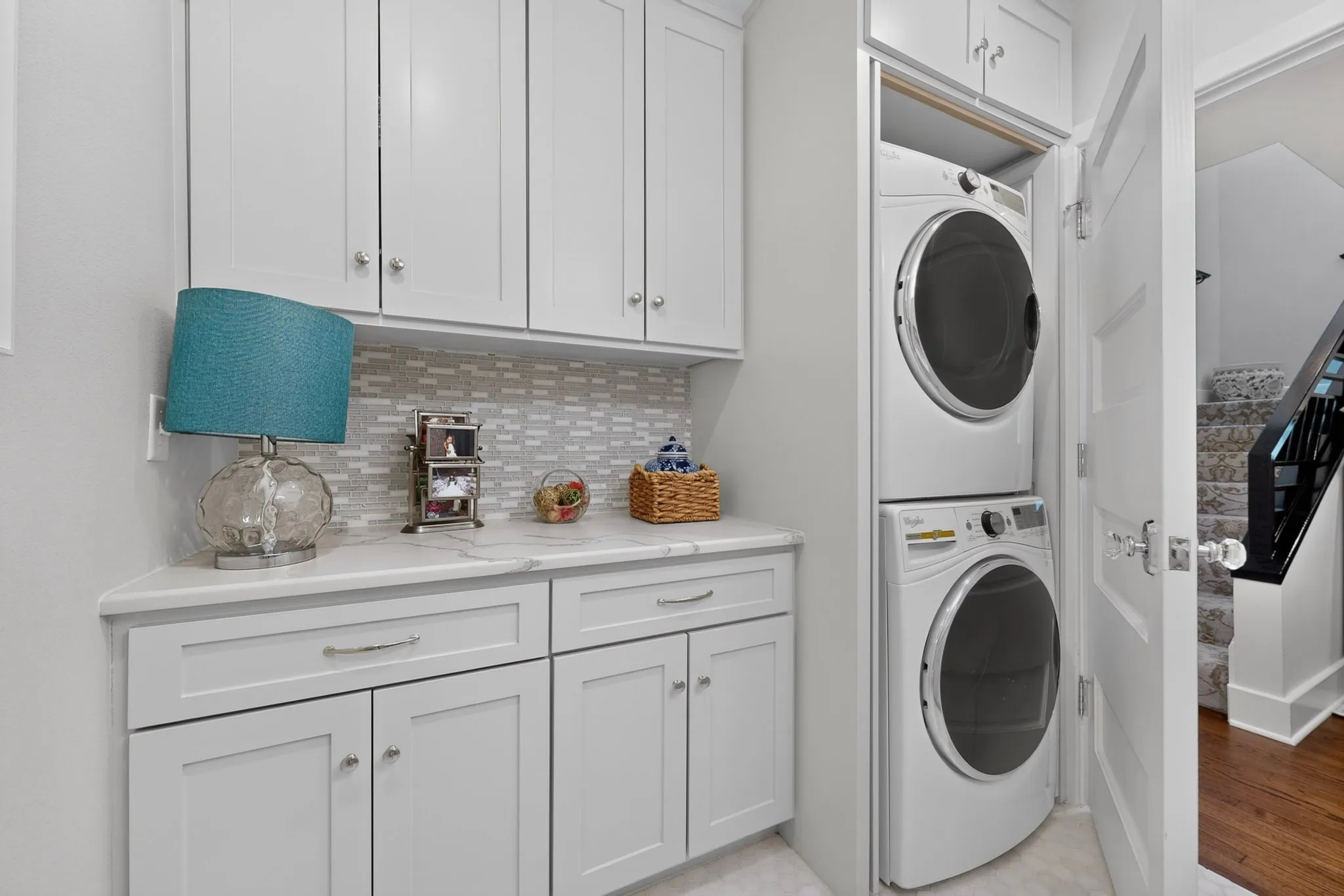 White shaker cabinetry with chrome hardware, countertop space, and a stacked washer and dryer
