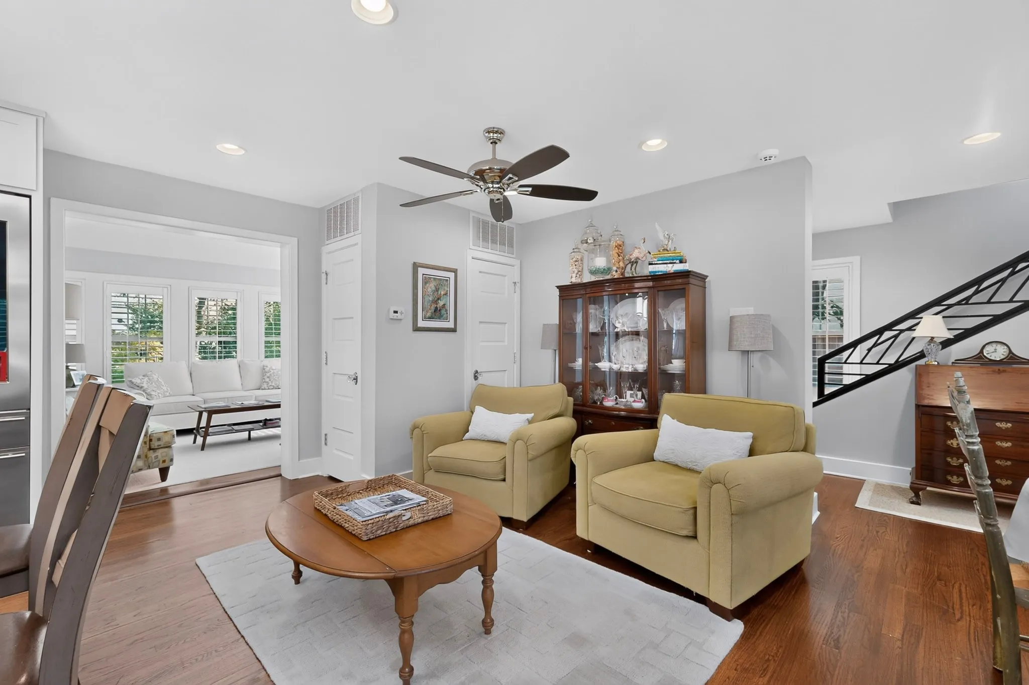 Bright, open living area featuring hardwood flooring, a ceiling fan with brushed nickel finish, recessed lighting, and French doors with transom windows providing natural light