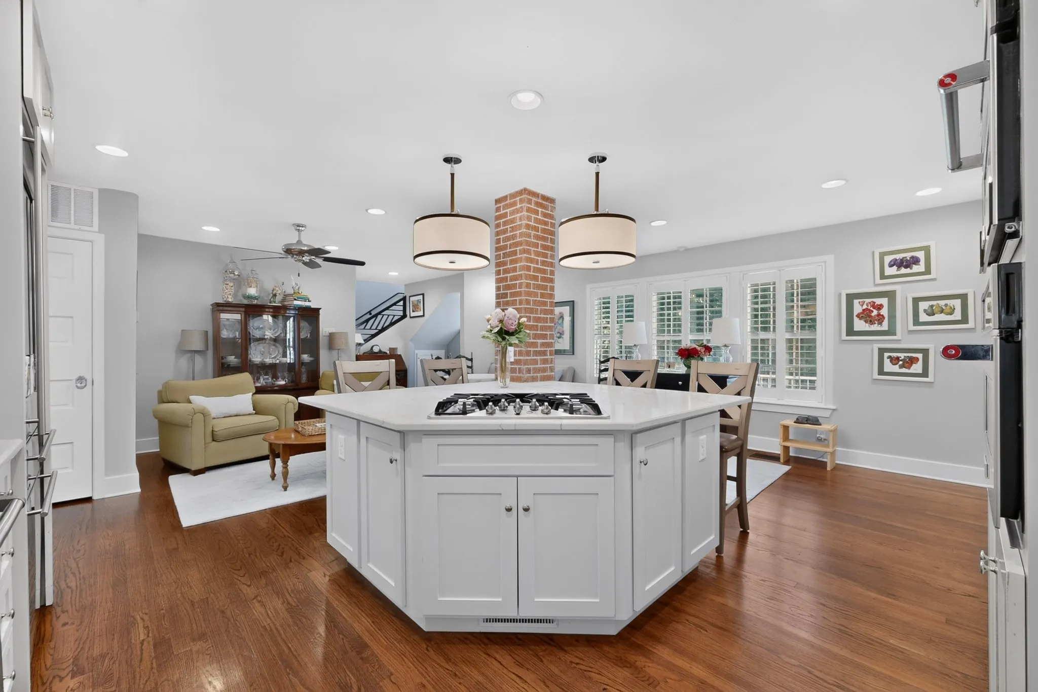 Expansive kitchen island with a built-in cooktop, white cabinetry, and a light-toned countertop, complemented by two pendant lights