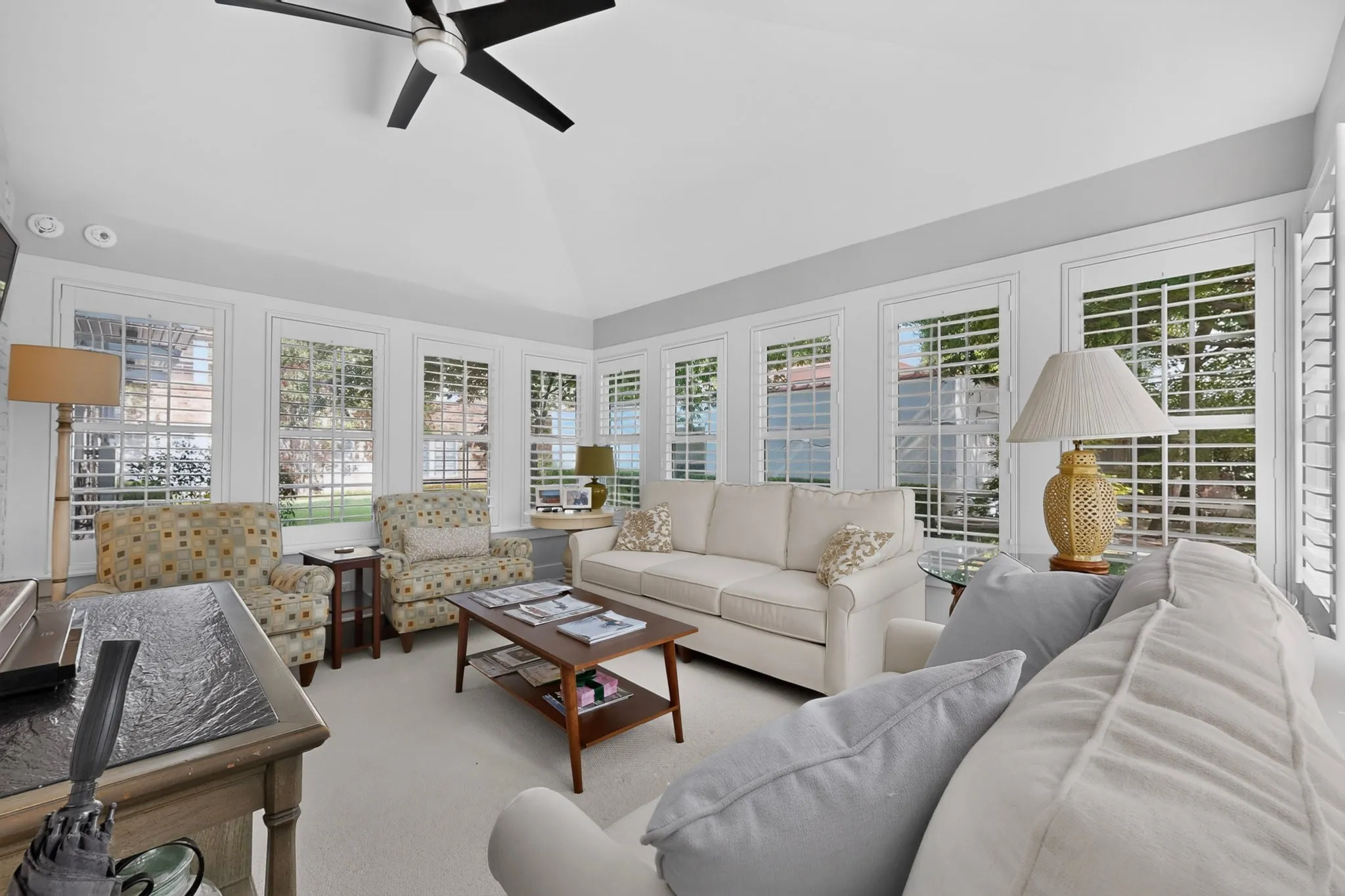 Vaulted ceiling with a ceiling fan, recessed lighting, white window shutters, and perimeter windows