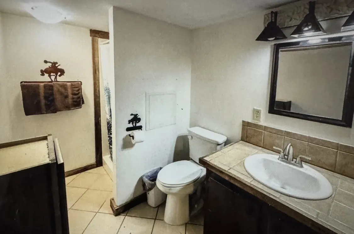 CABIN BATH Vanity with a surface-mount sink and tile countertop, tile flooring, and a stand-up shower with a clear enclosure