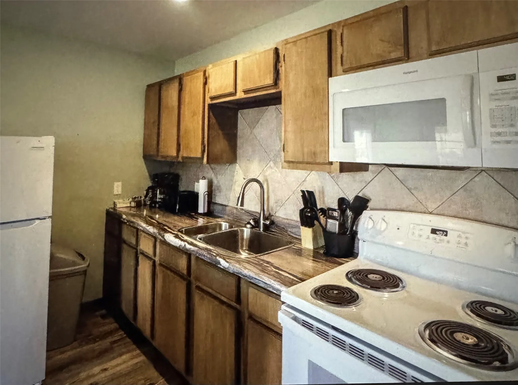 Suite Kitchen Wood-finish cabinetry, tile backsplash, laminate countertops, and wood-finish flooring