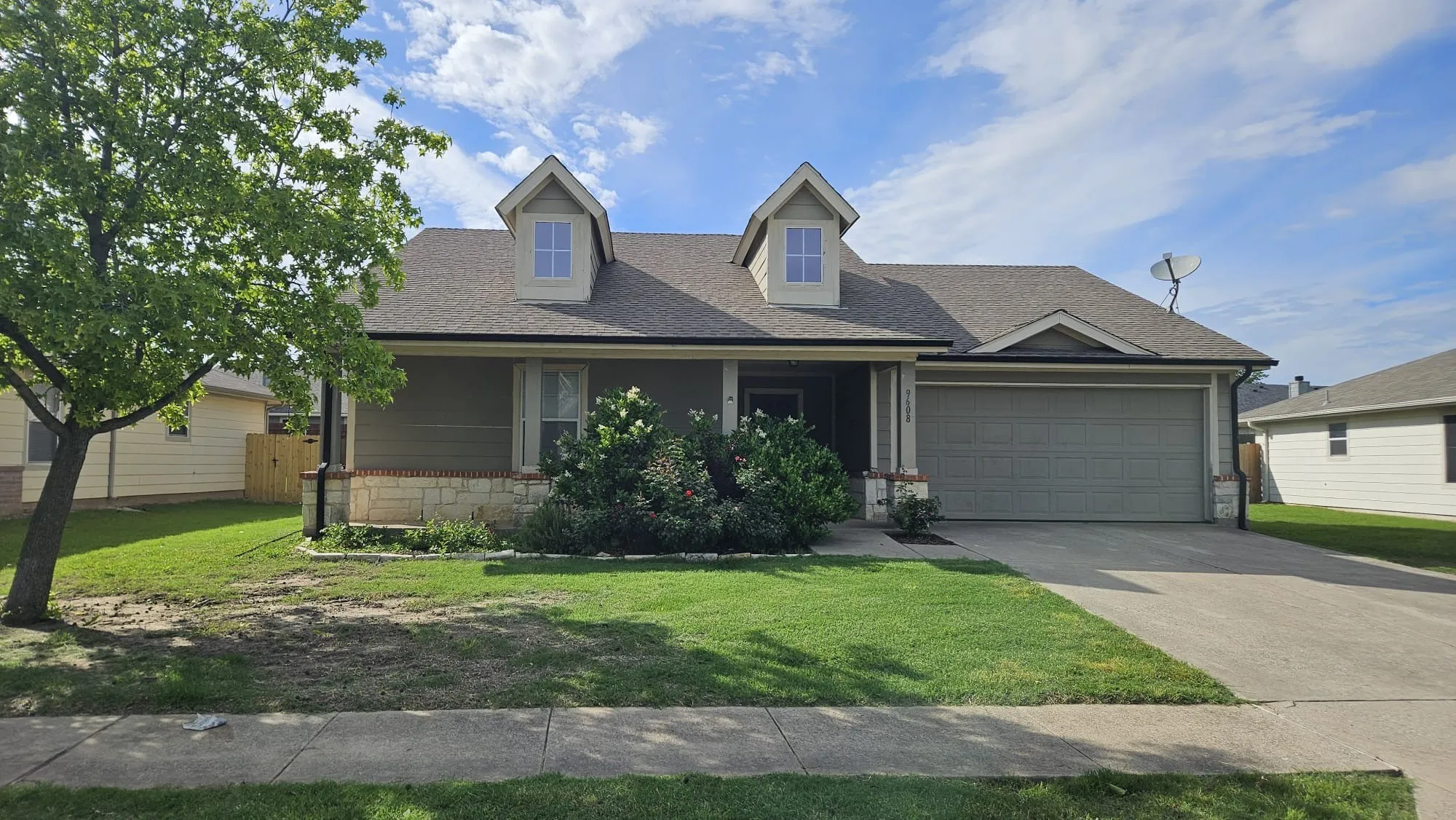 Single-story residence featuring a two-car garage, dormer windows, a covered entry, and stone-finish accents