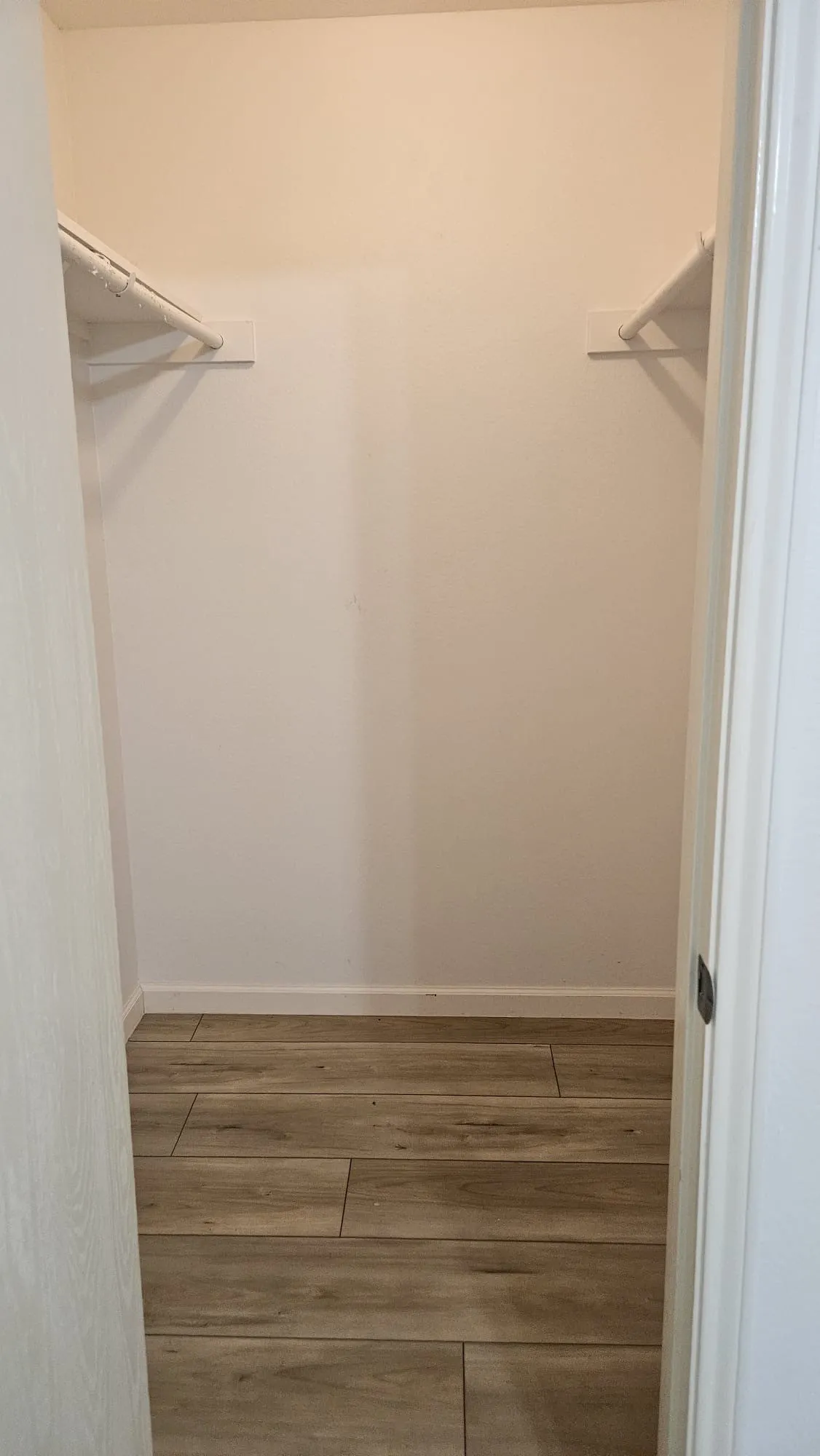 Wood-finish tile flooring with white walls and built-in closet shelving