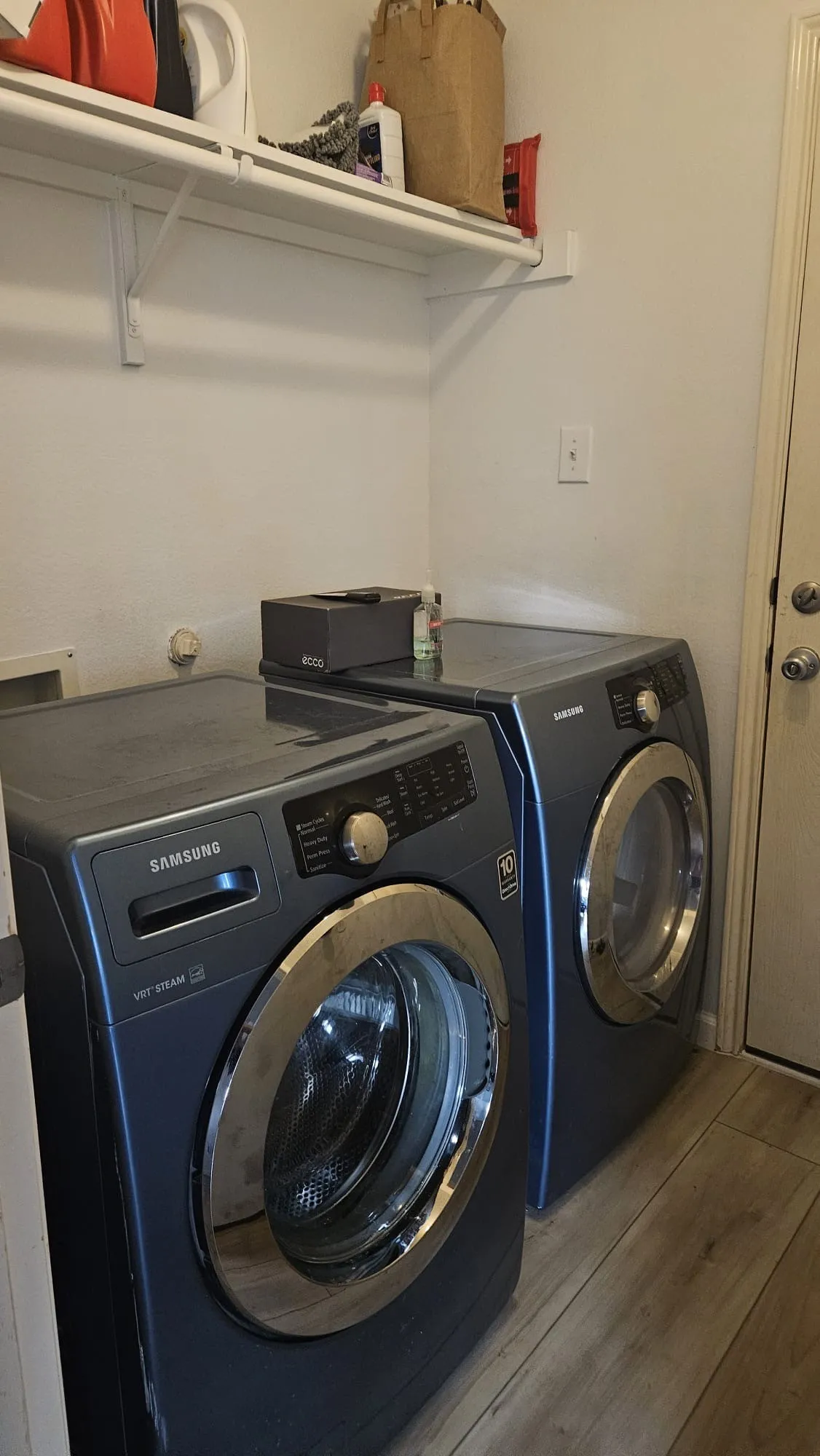 Laundry area with wood-finish flooring and a wall-mounted shelving unit