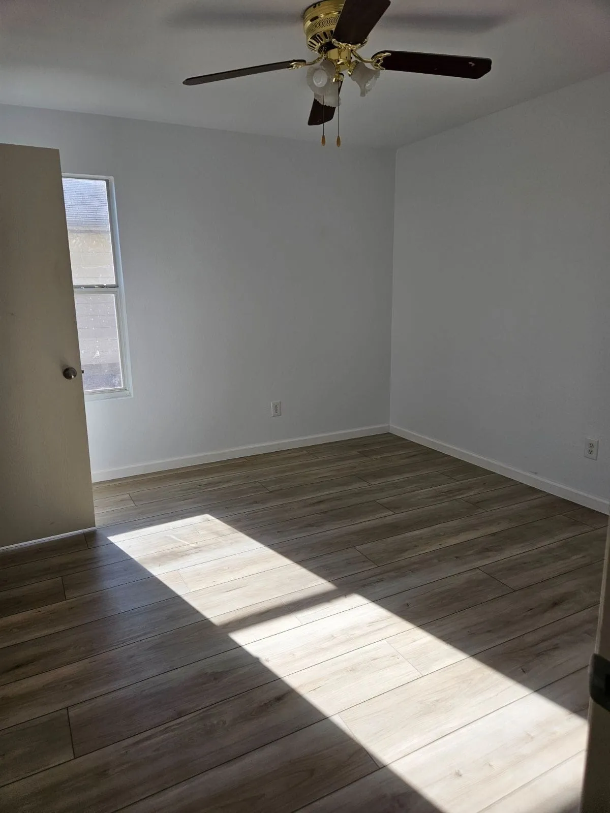 Wood-finish flooring, ceiling fan with integrated lighting, and a single window