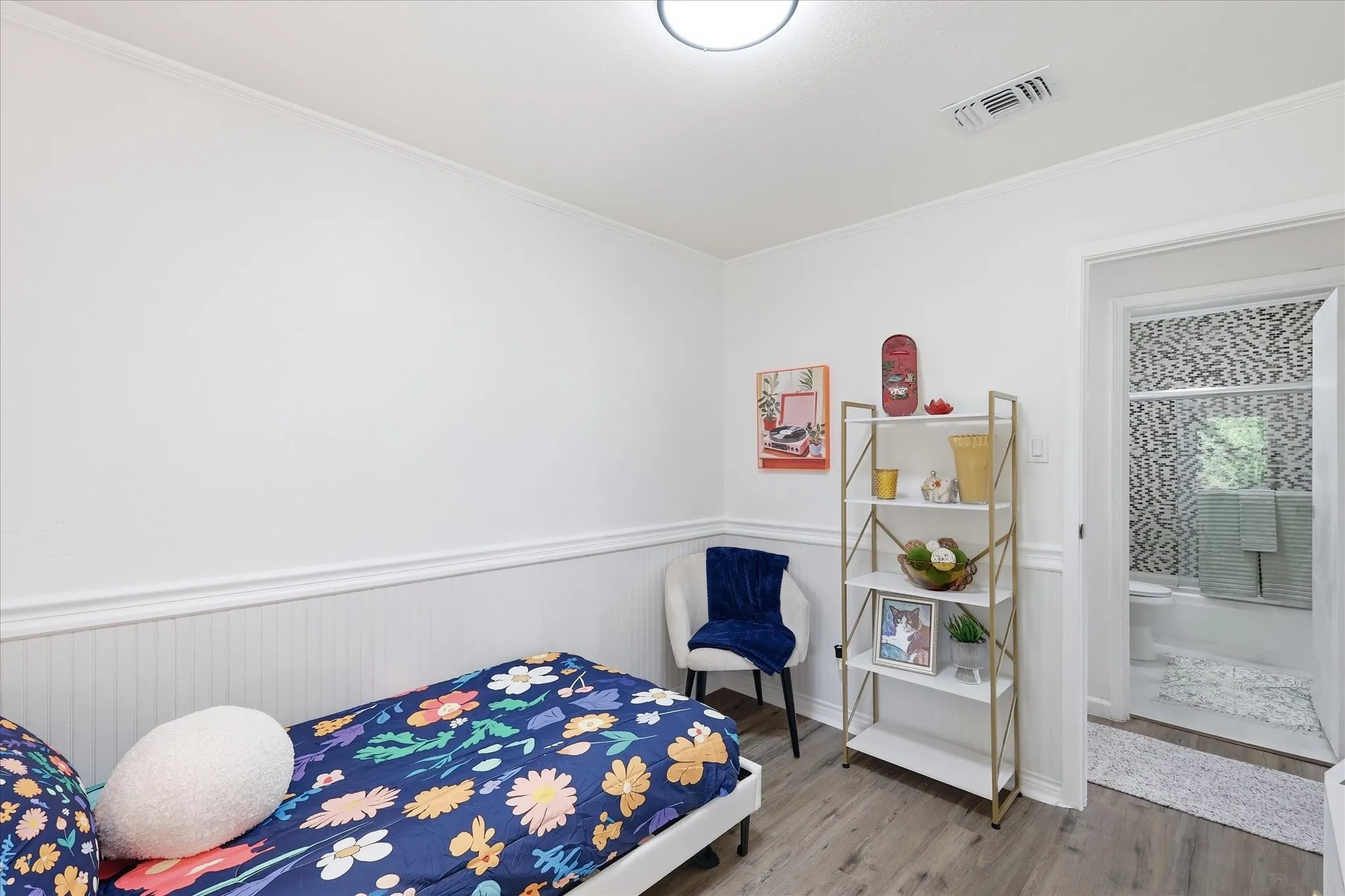 Wood-finish flooring, wainscoting, crown molding, and a full bathroom with mosaic tile