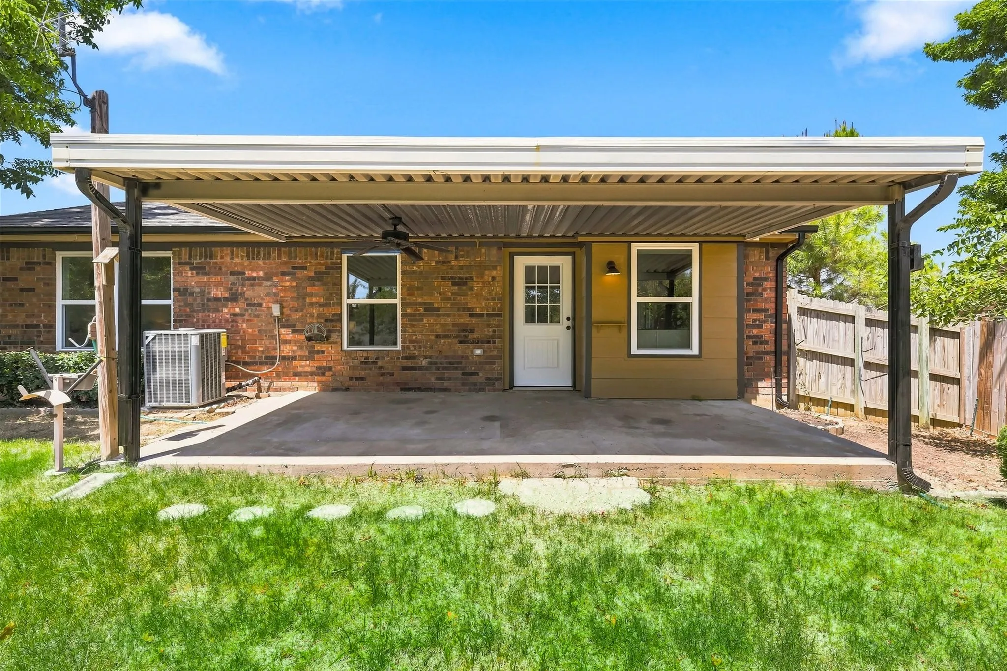 Covered patio with an outdoor ceiling fan, brick and siding exterior, and a privacy fence