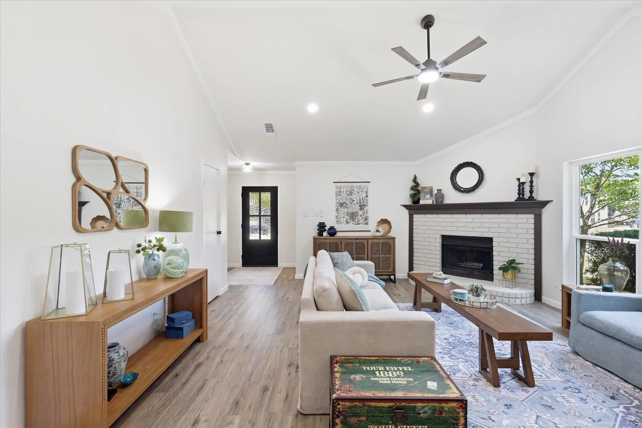 Vaulted ceiling with a ceiling fan, white brick fireplace with dark wood mantel, wood-finish flooring, and recessed lighting