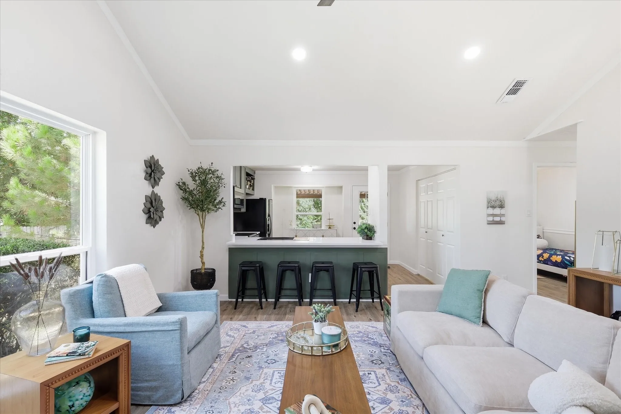 Vaulted ceilings with recessed lighting, large picture windows, wood-finish flooring, and an open-concept layout with a breakfast bar
