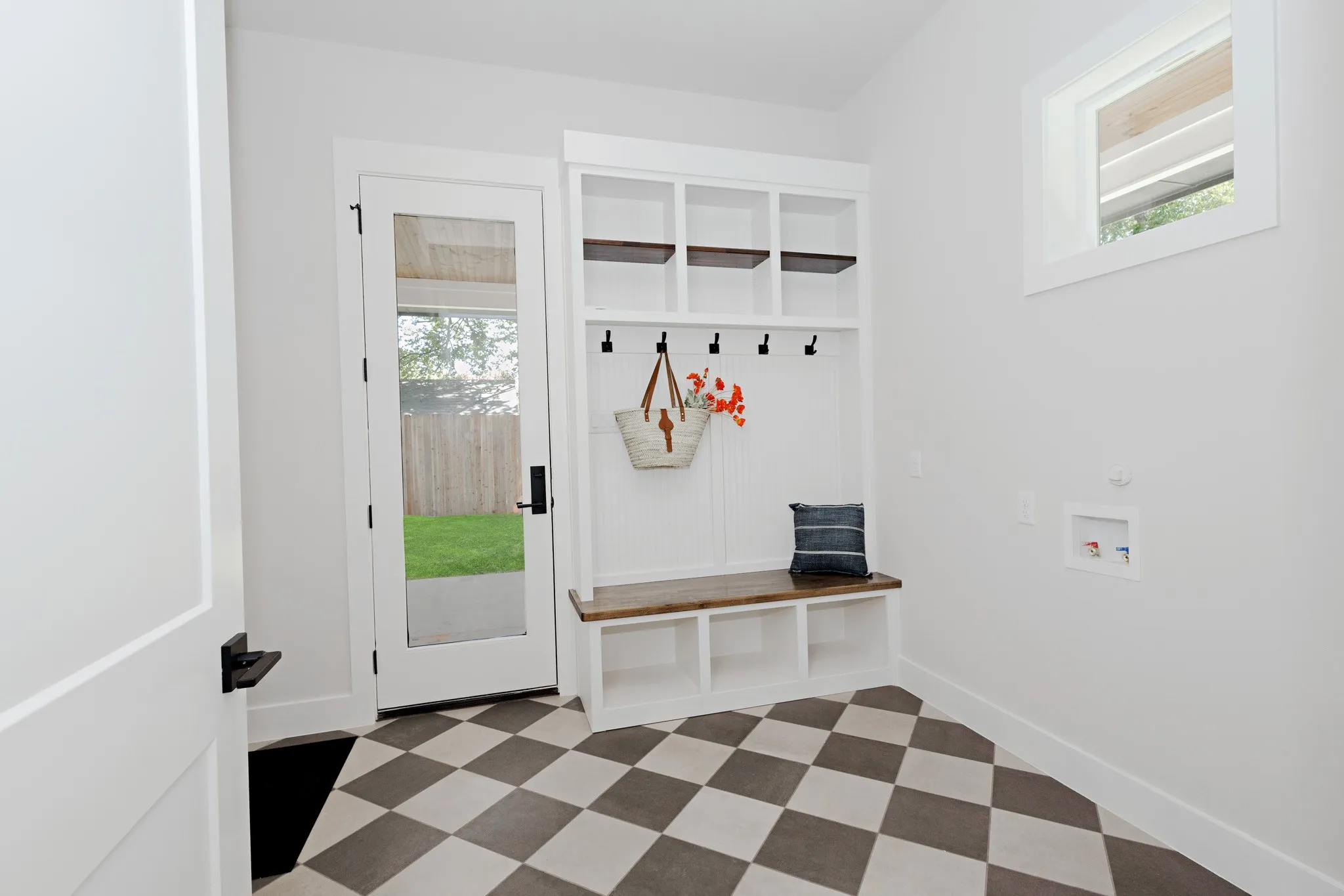 This Laundry Room offers a Built-in Custom Mud Bench with Shelves and Additional Shelving and space to stay organized.