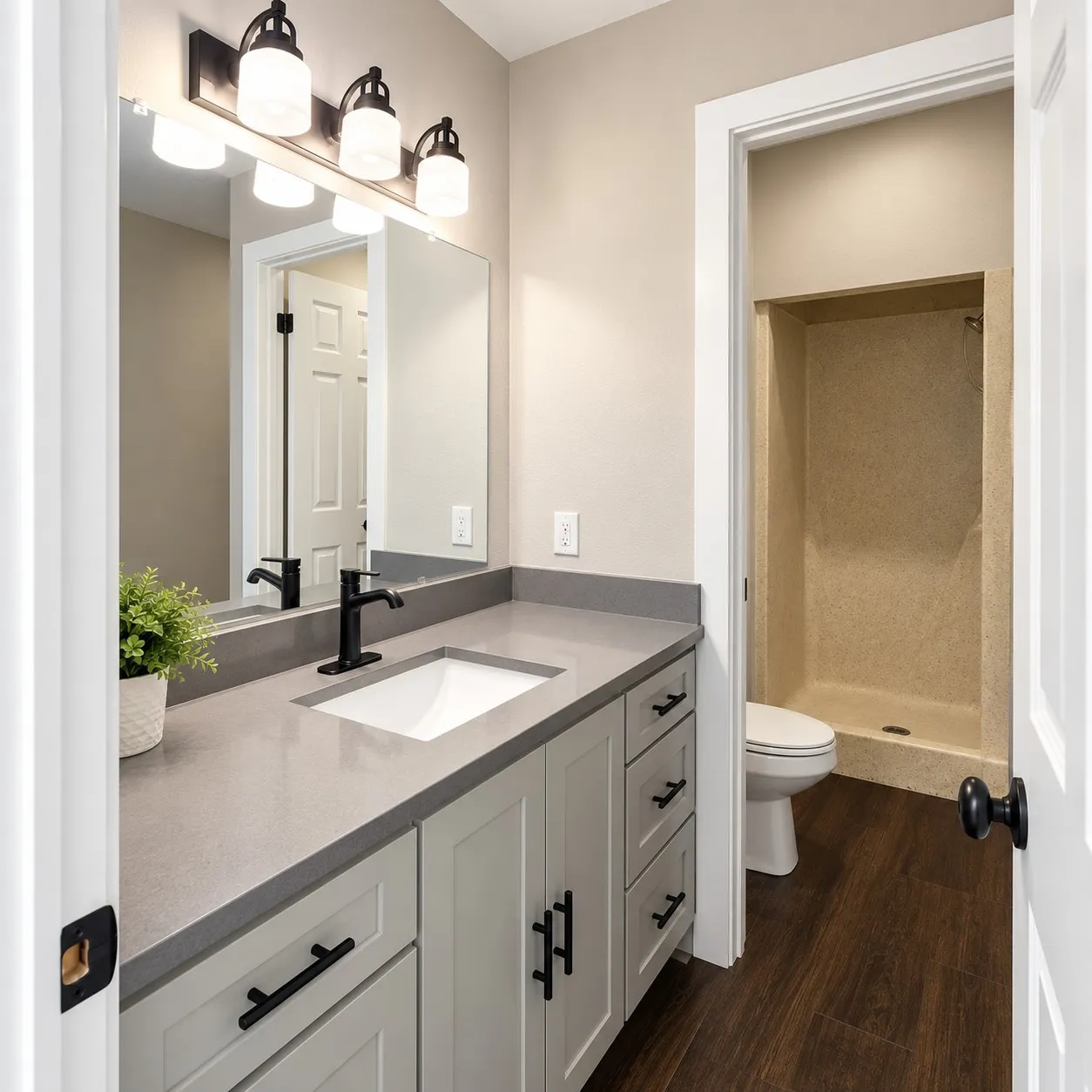 Bathroom featuring a light gray vanity with a single basin, a dark countertop, a matte black faucet, and wood-finish flooring
