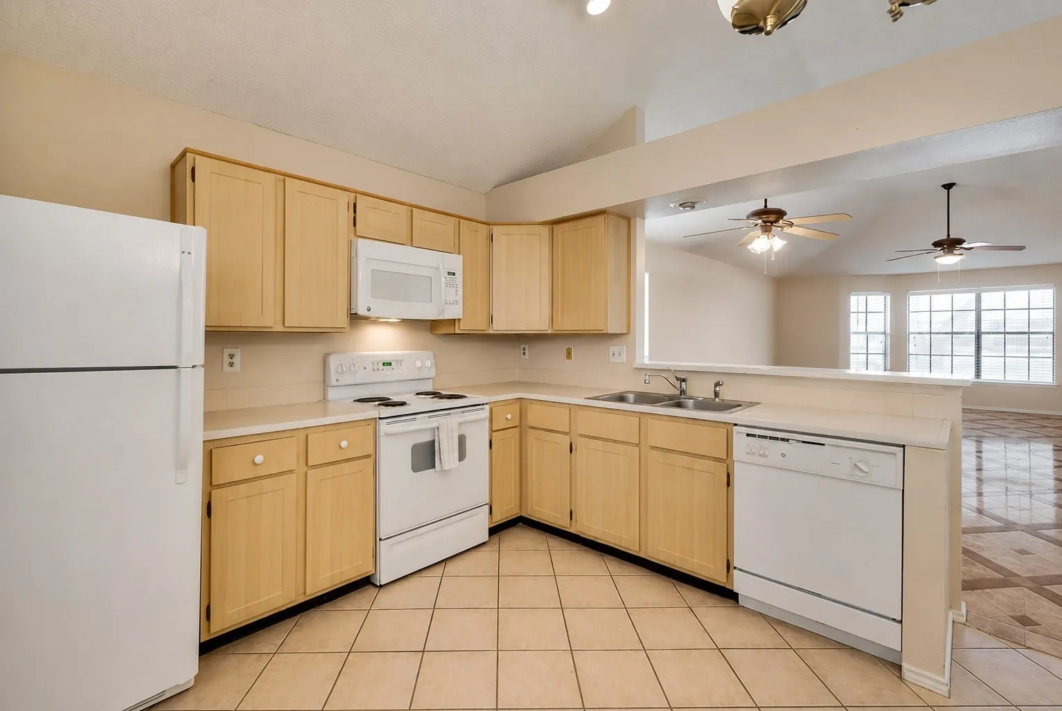 Kitchen featuring wood-finish cabinetry, white appliances, and a double basin sink