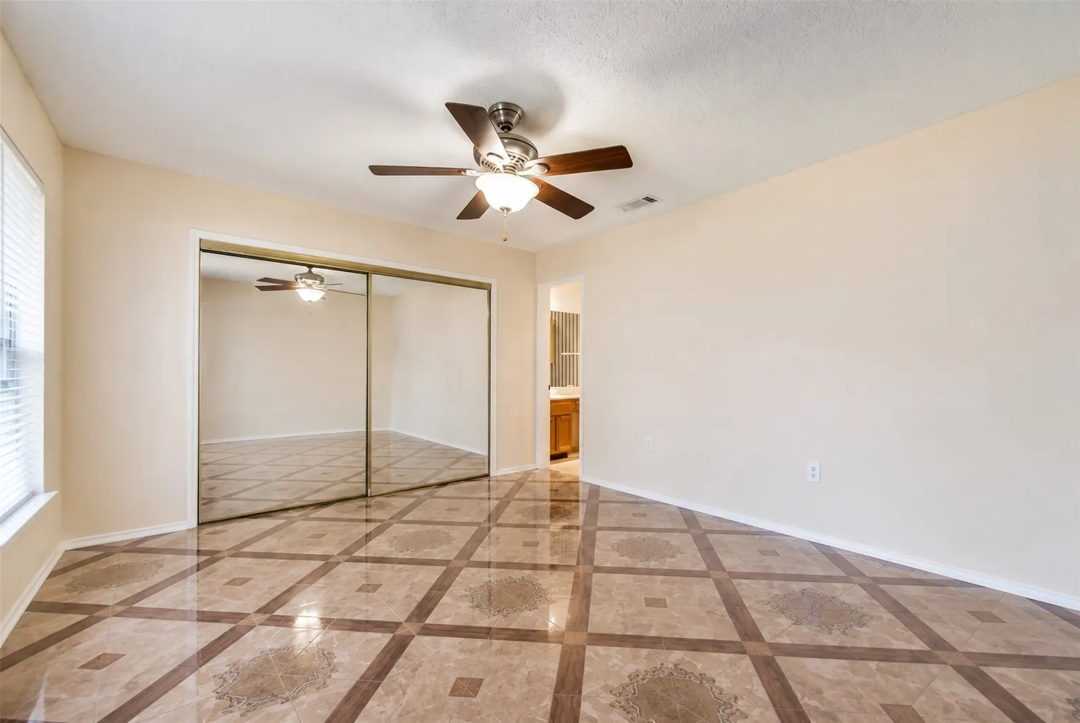 Tile flooring with a geometric pattern, mirrored closet doors, a ceiling fan with integrated lighting, and a window with blinds