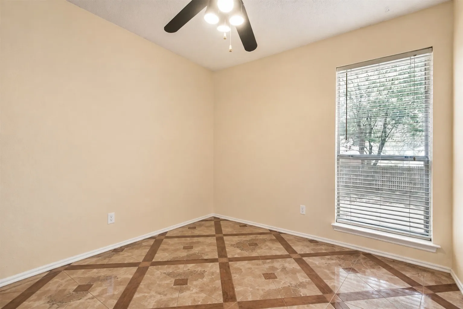 Patterned tile flooring, single window with blinds, ceiling fan with integrated lighting, neutral wall tones, white trim
