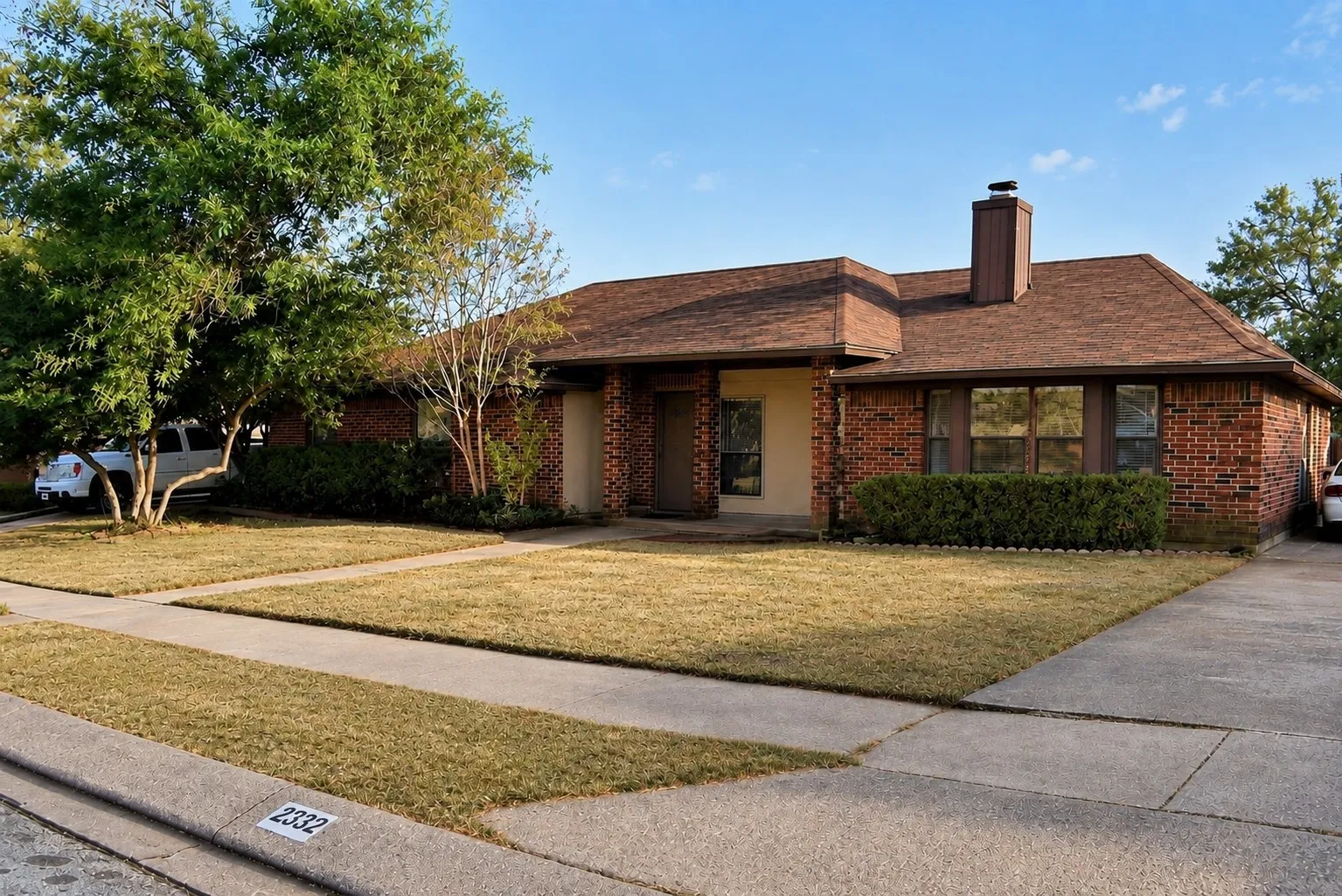 Brick exterior with stucco accents, an attached chimney, and a brown shingle roof