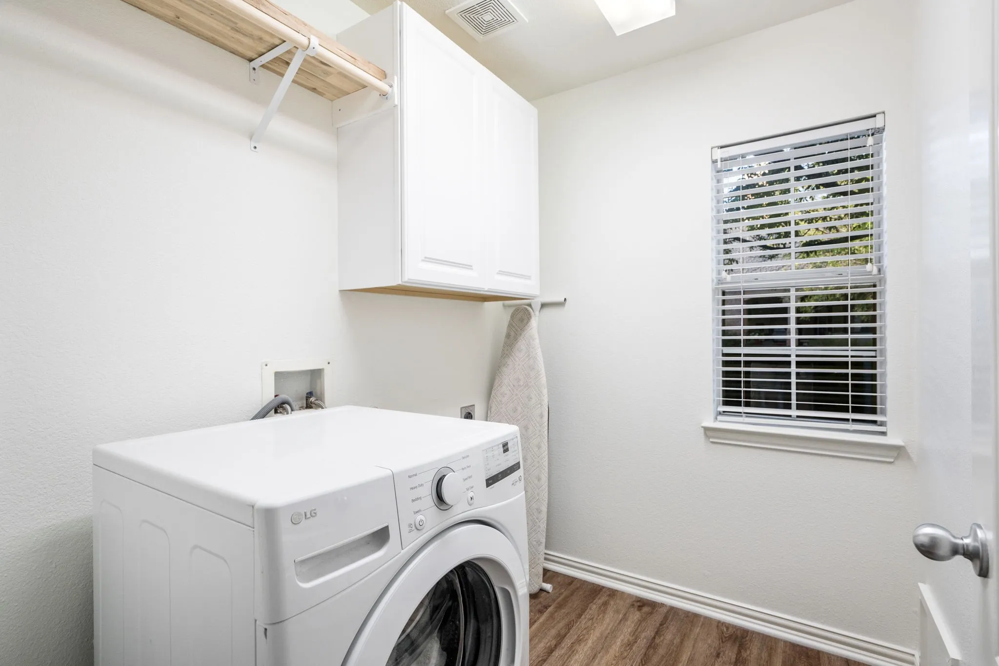 Remodeled laundry with new cabinets, drip rod for hanging dry, shelf above for more storage. Plenty of room for an ironing board, window allows light in. Conveniently located within the home. Wooden flooring.