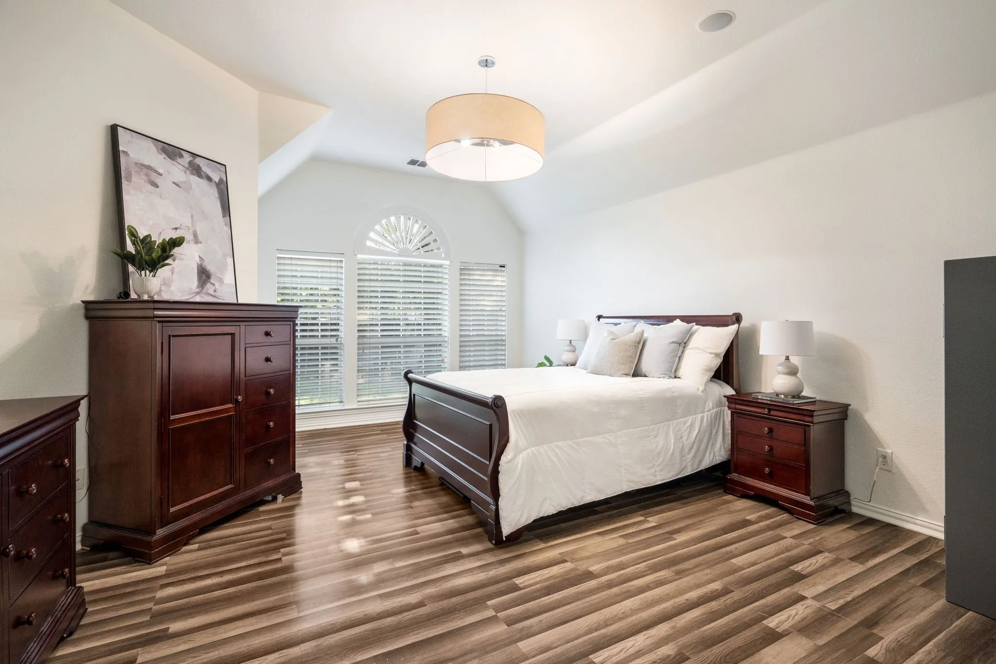 Spacious primary owners suite with wooden flooring, a brand new designer large drum light from West Elm and plenty of room for all of your Texas sized furniture. Enjoy room for a seating area by your bedroom windows. Open to primary ensuite bath and privately tucked into the home.