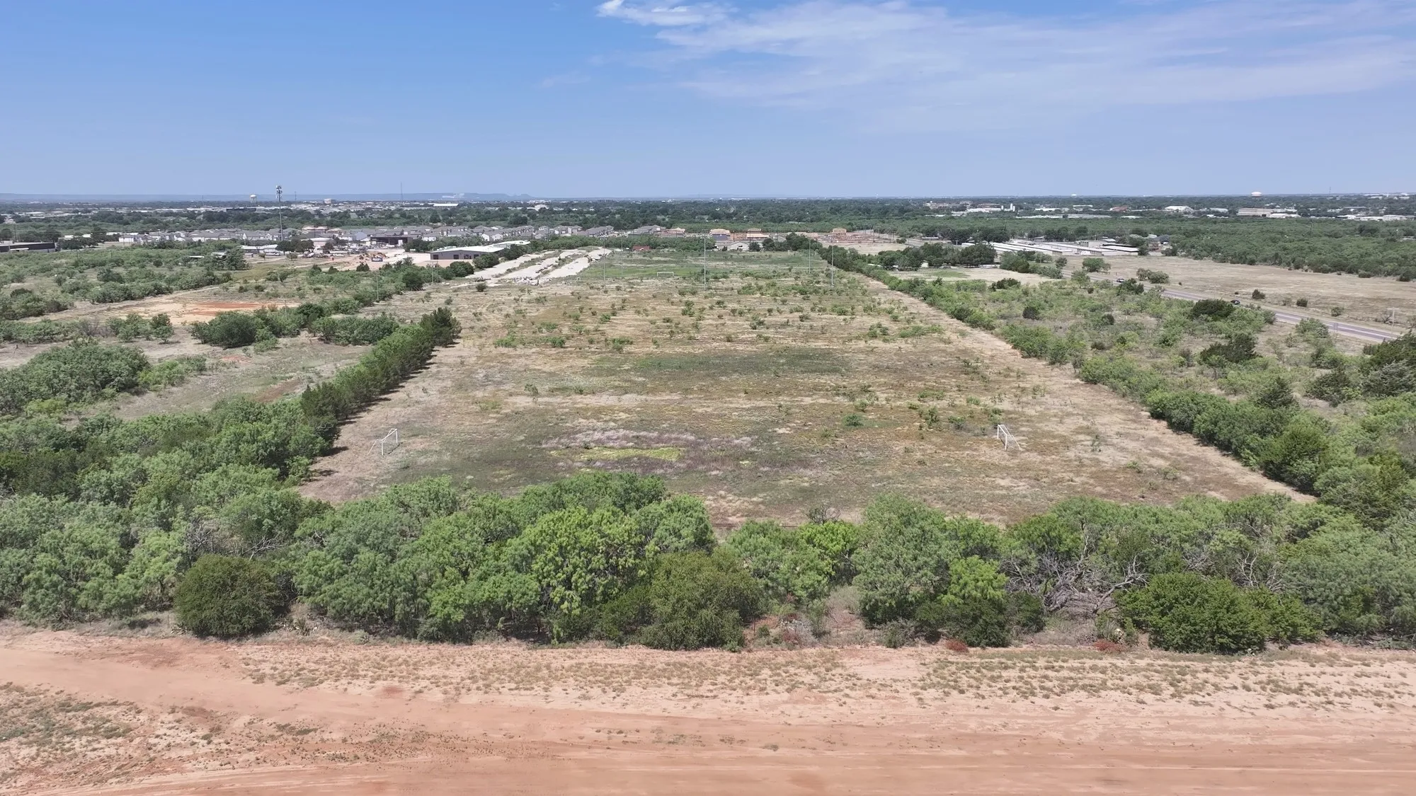 Expansive undeveloped land featuring natural vegetation and surrounding tree lines