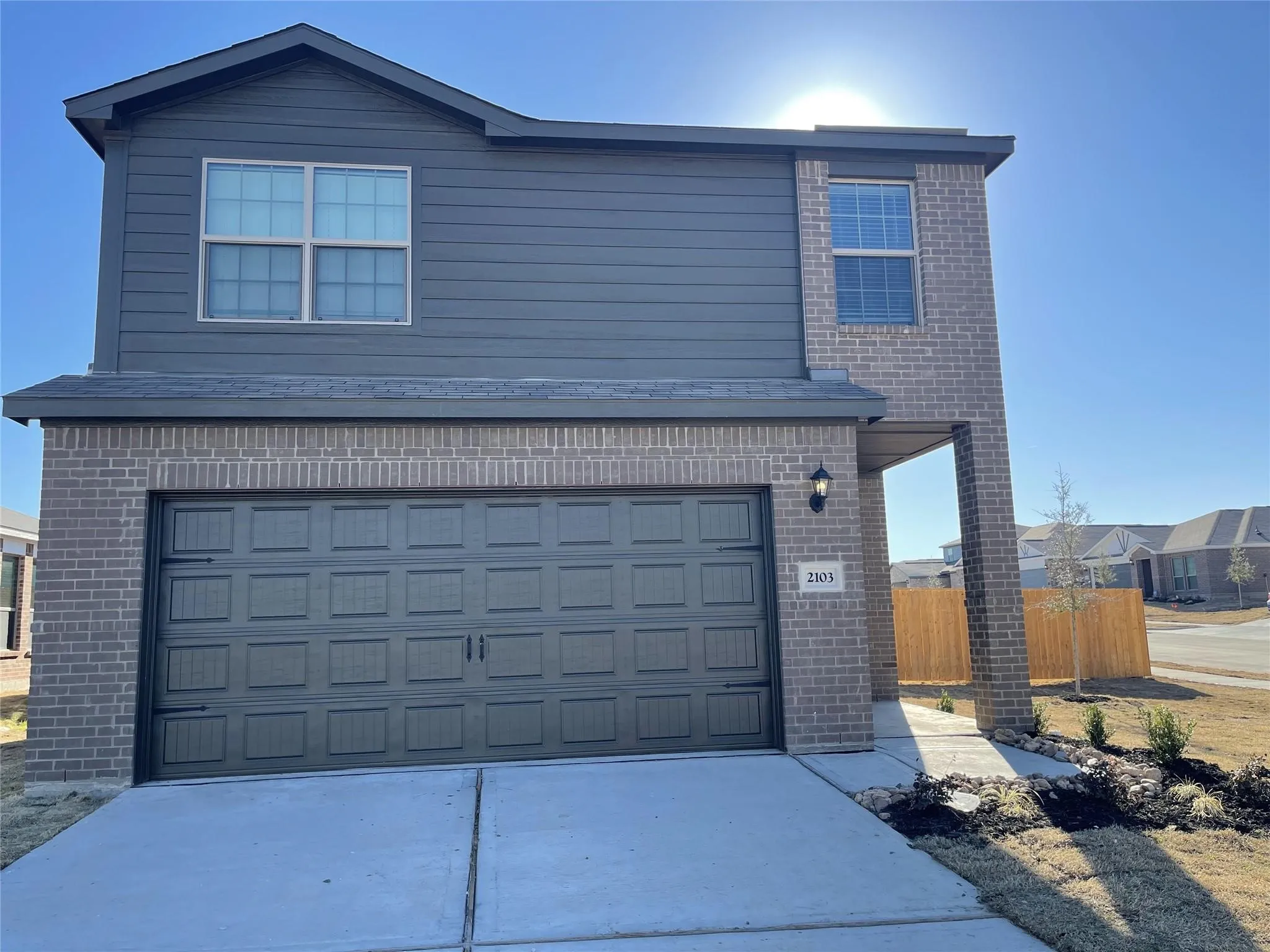 Two-story residence featuring a brick and siding exterior, an attached garage, a concrete driveway, and a walkway leading to the entry