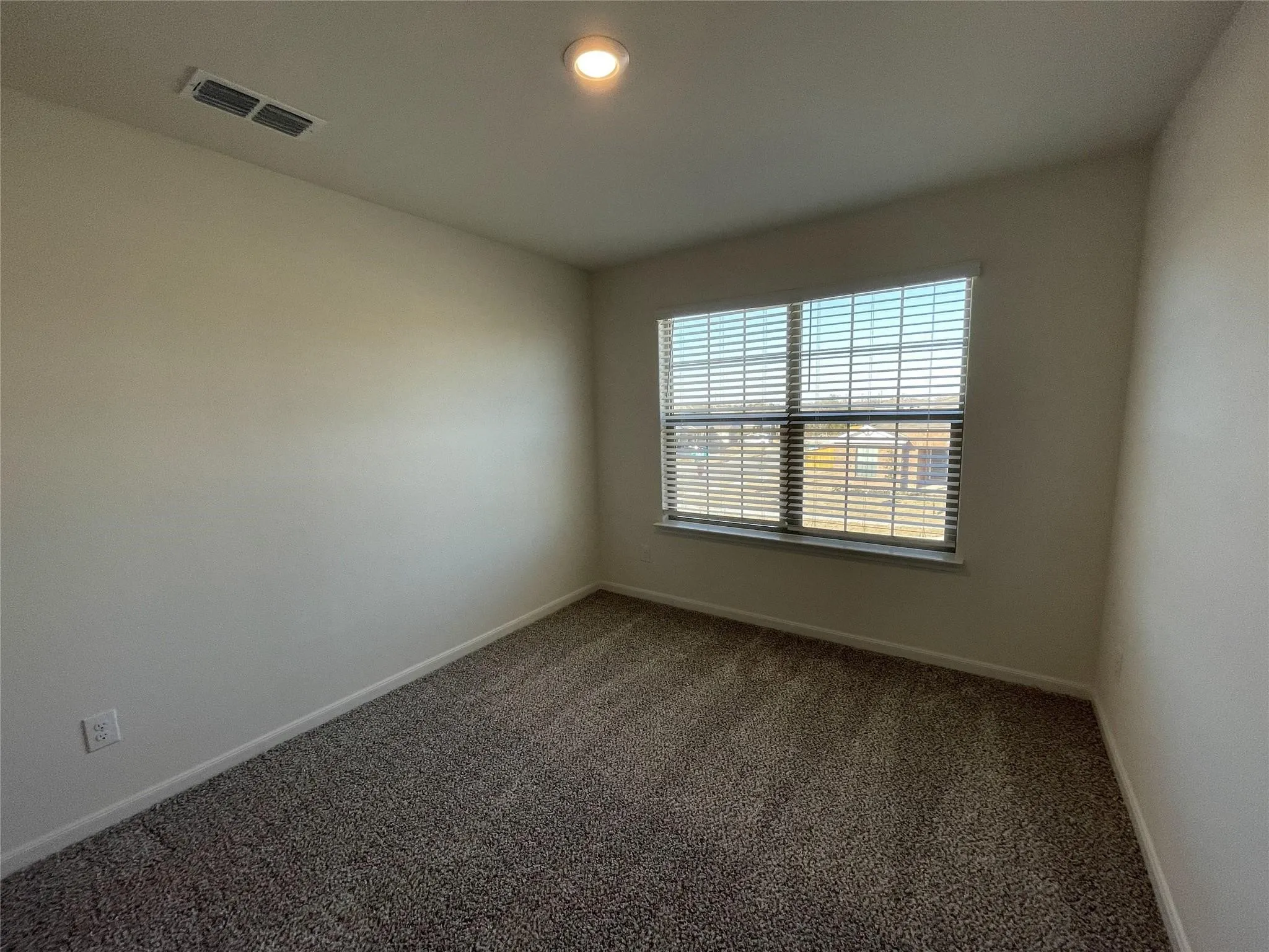 Recessed ceiling lighting, textured carpeting, neutral wall finishes, and a single window with horizontal blinds