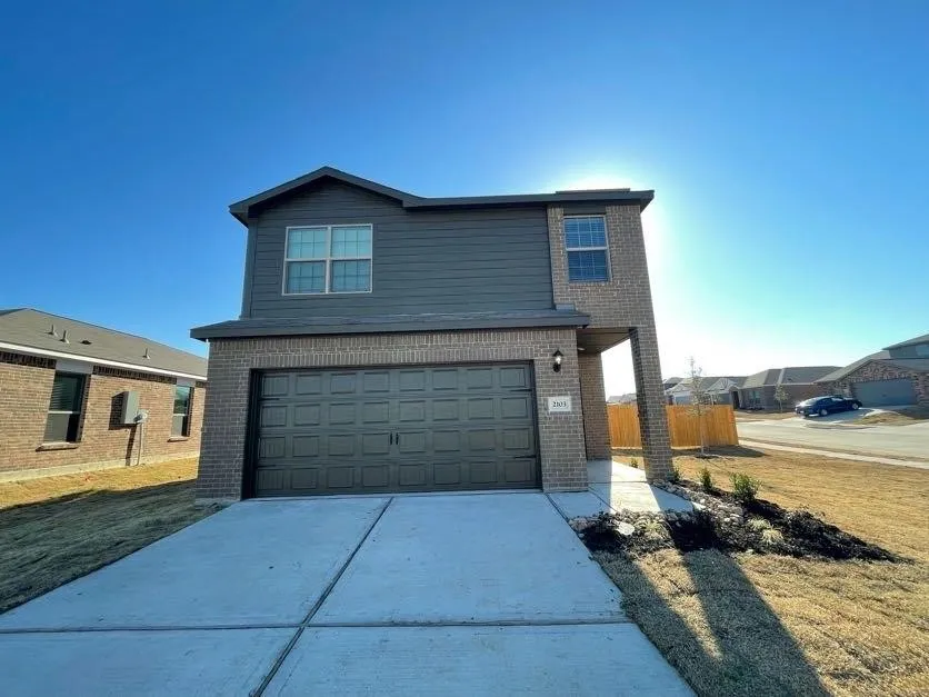 Two-story exterior with brick and siding facade, an attached garage, and a concrete driveway