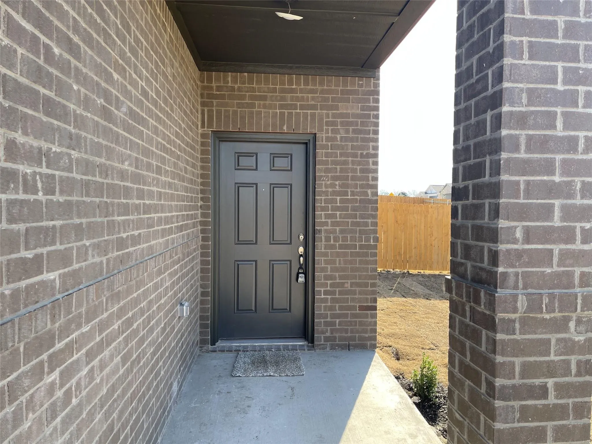 Brick exterior with dark gray panel door and concrete porch