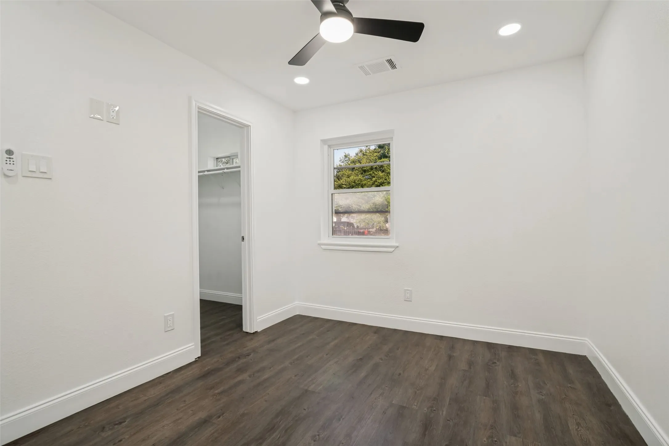 Recessed lighting, dark wood-finish flooring, white trim, a ceiling fan, and a built-in closet