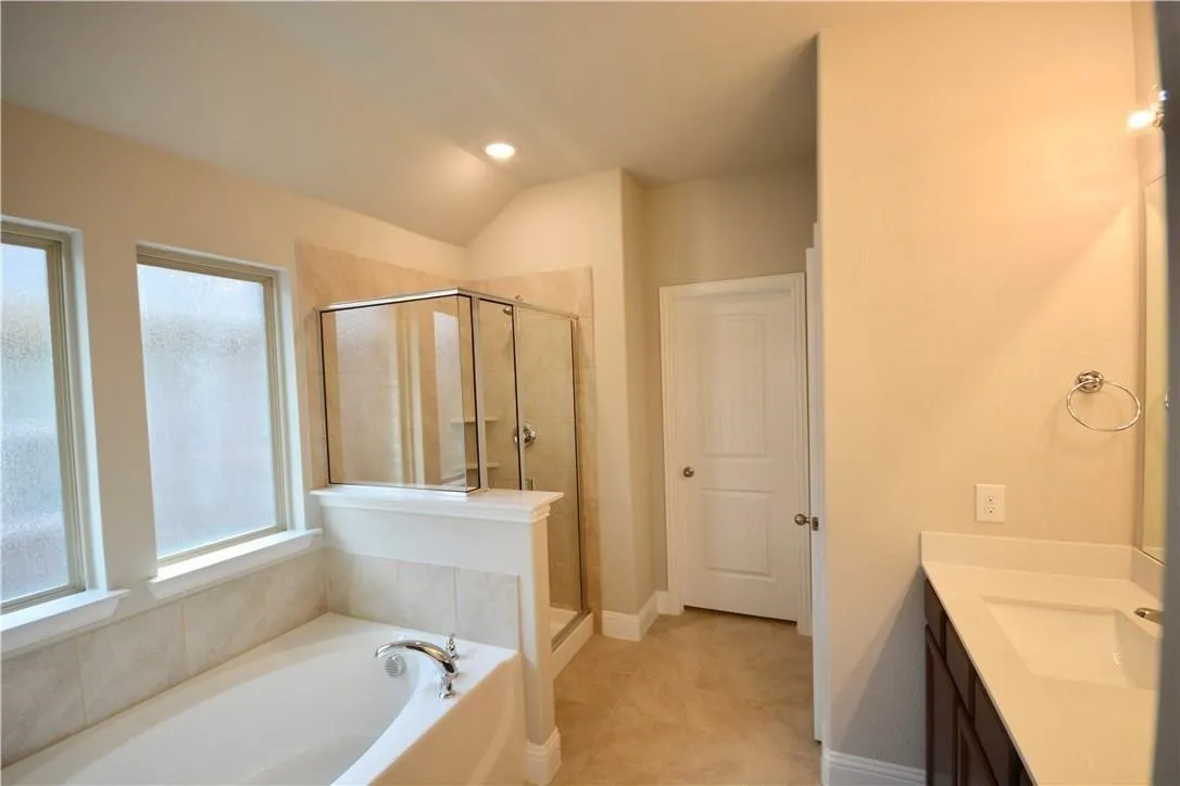 Recessed lighting, vaulted ceiling, glass-enclosed shower, built-in bathtub, and dual windows