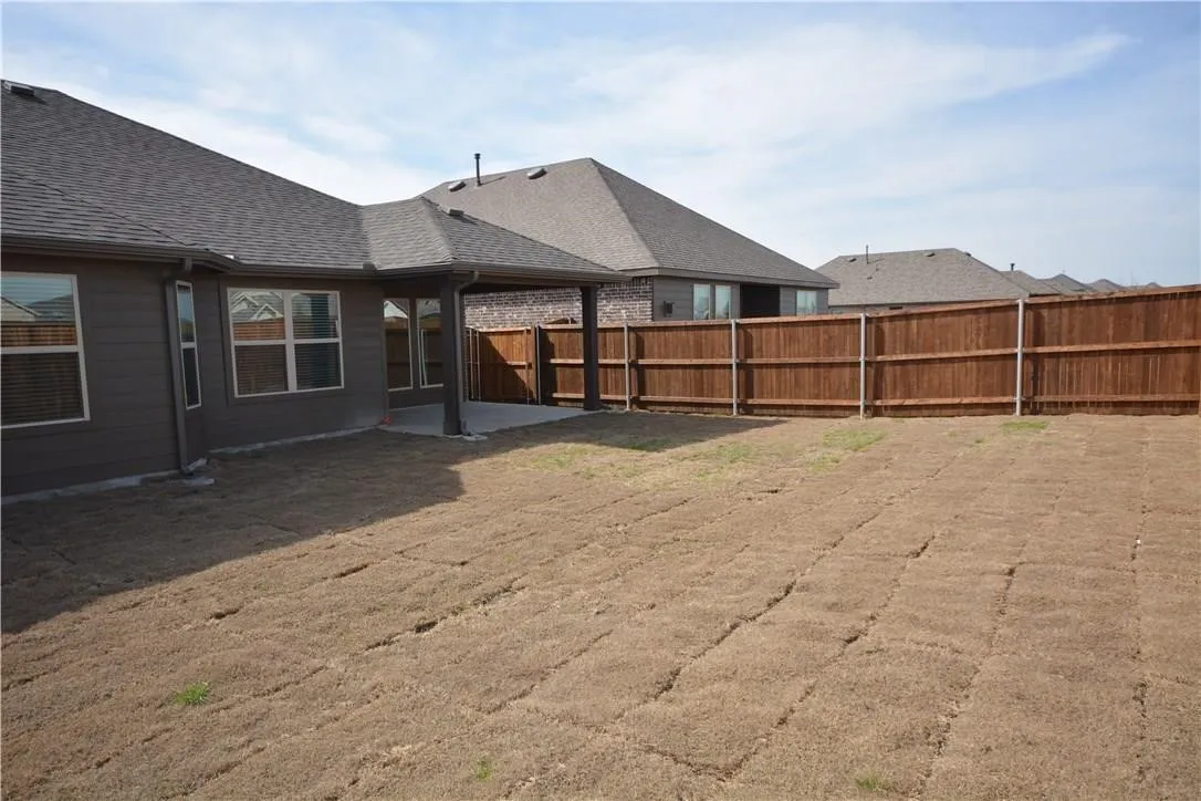 Private backyard with a covered patio, new sod, and wood fencing