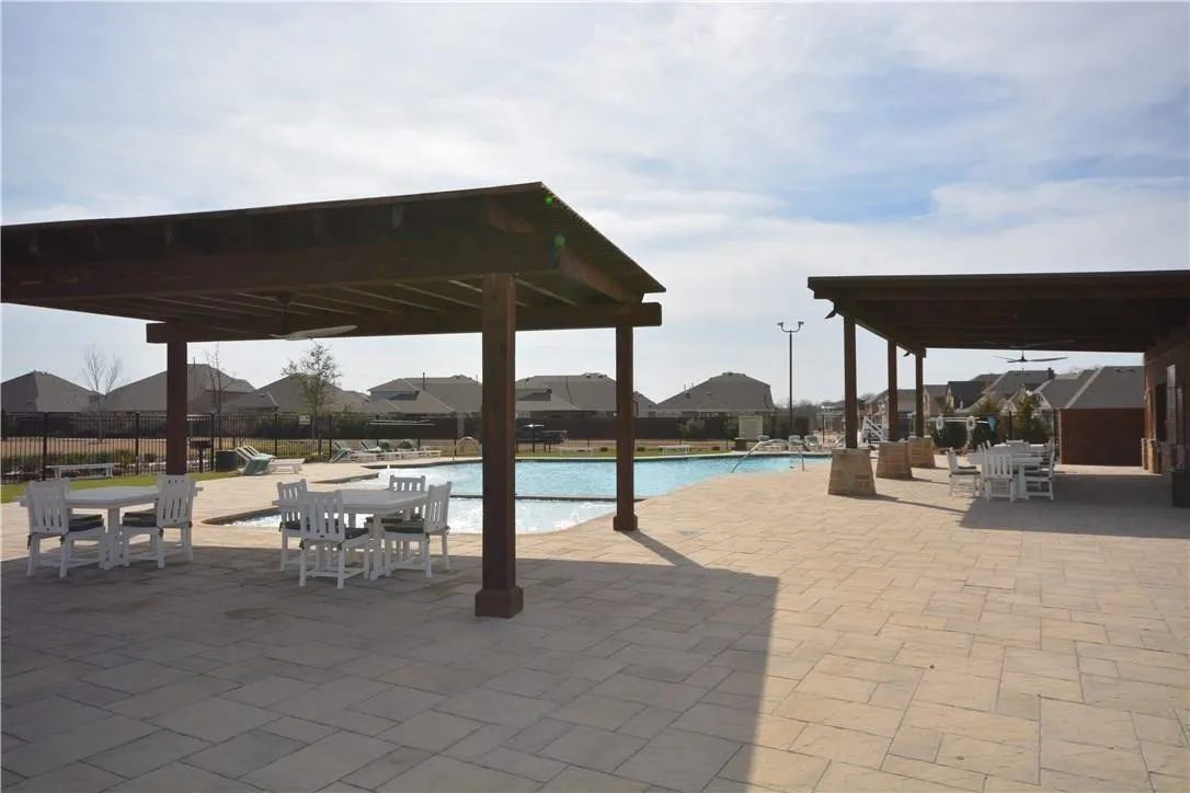 Expansive pool area featuring a perimeter fence, large swimming pool, and multiple covered pergolas