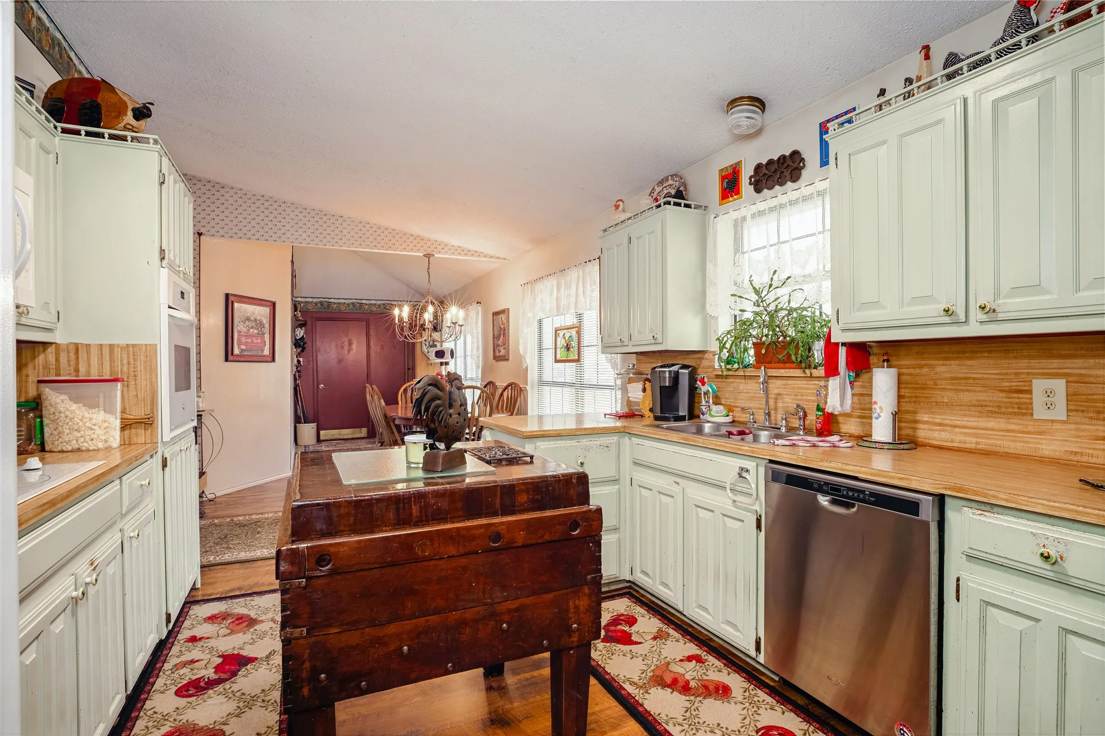 Kitchen featuring light-toned cabinetry, wood-finish countertops, stainless steel dishwasher, and recessed built-in microwave
