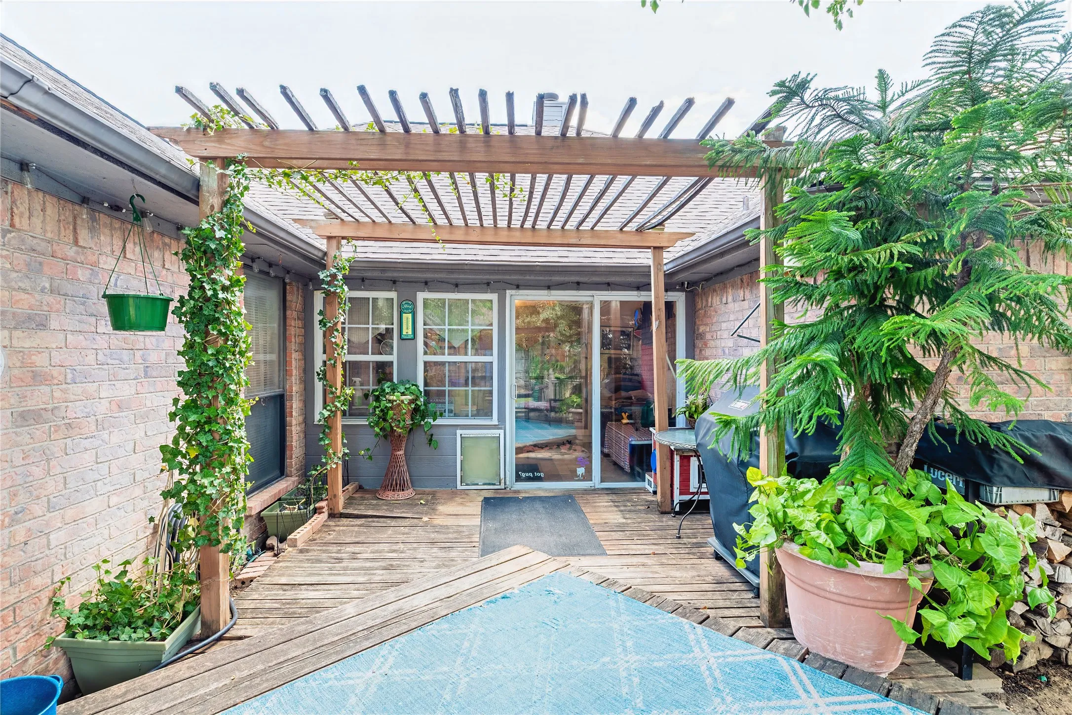 Wood pergola covering a wood-finish deck with brick exterior walls
