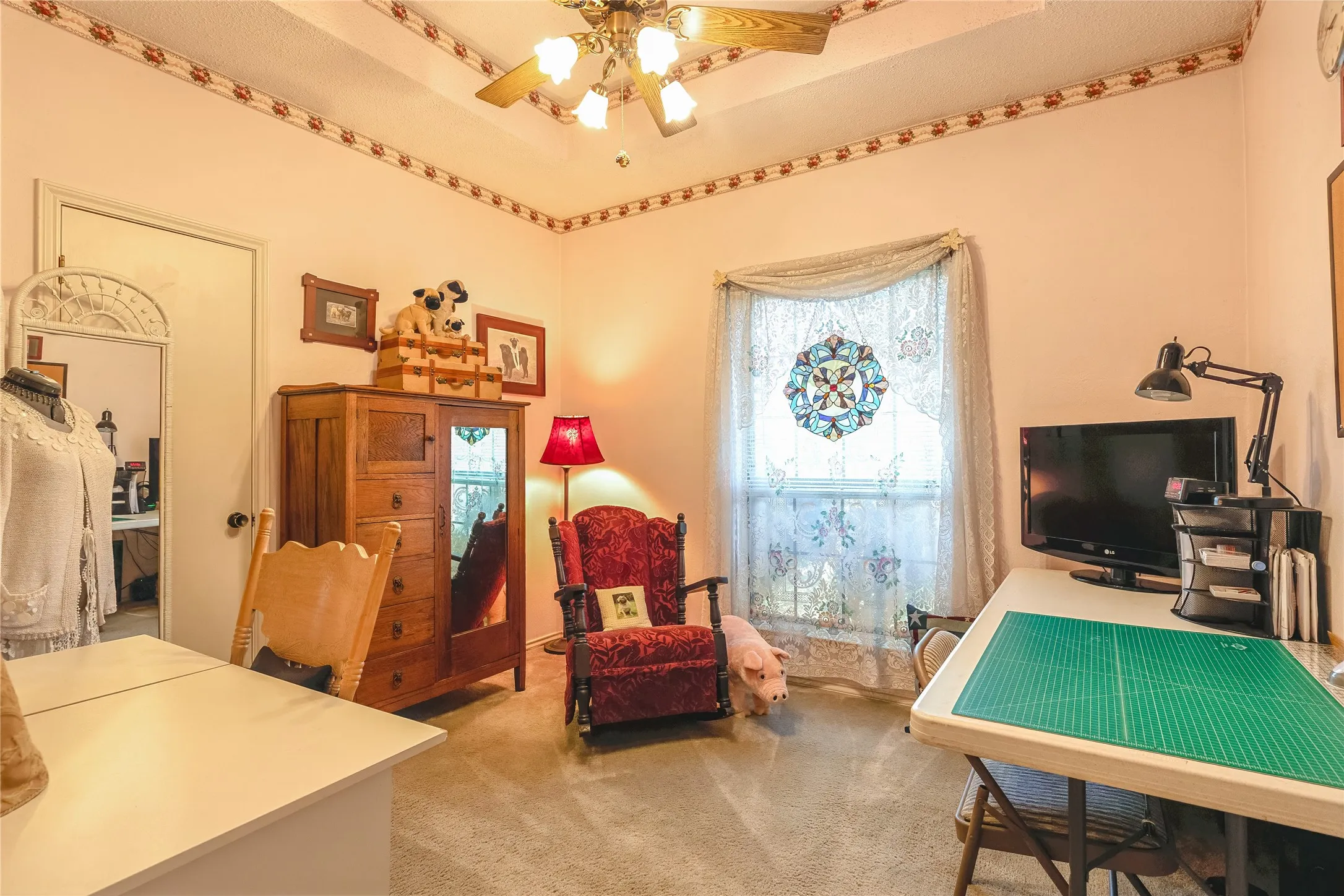 Vaulted ceiling with a ceiling fan light fixture, textured wall finishes, carpeted flooring, and a window with decorative glass