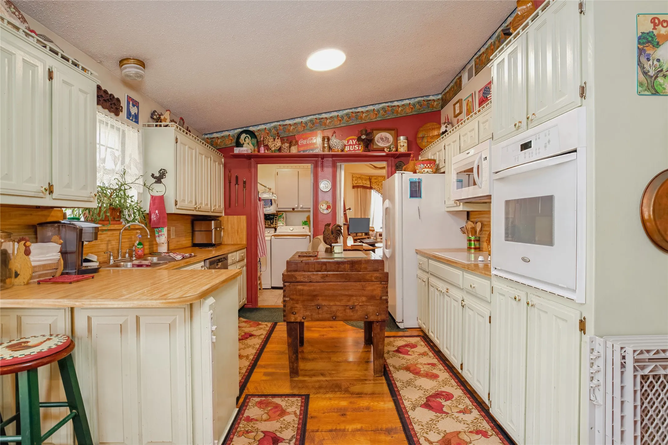 White cabinetry with beadboard paneling, light wood-finish countertops, and hardwood flooring