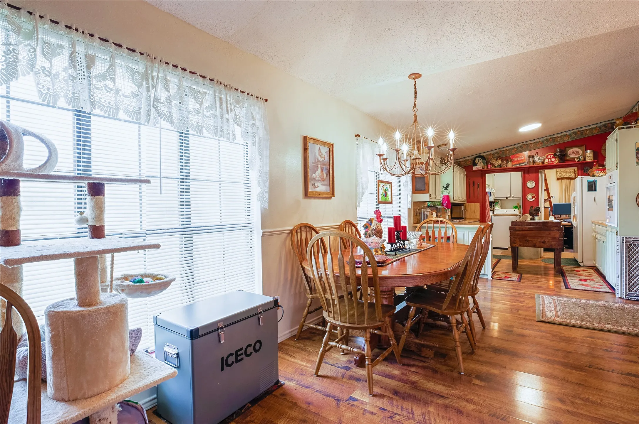 Wood-finish flooring throughout, large window with blinds, and a chandelier lighting fixture