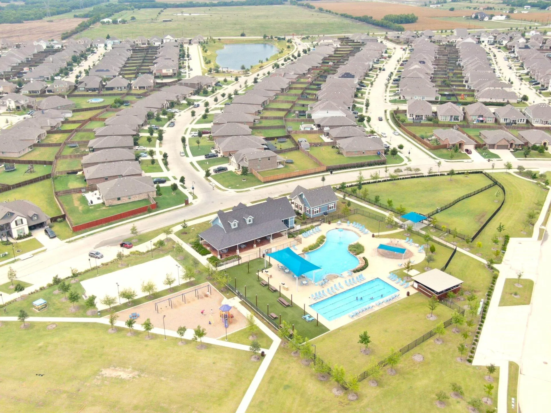 Community featuring a large pool, shaded pool deck, separate lap pool, playground, and extensive green spaces