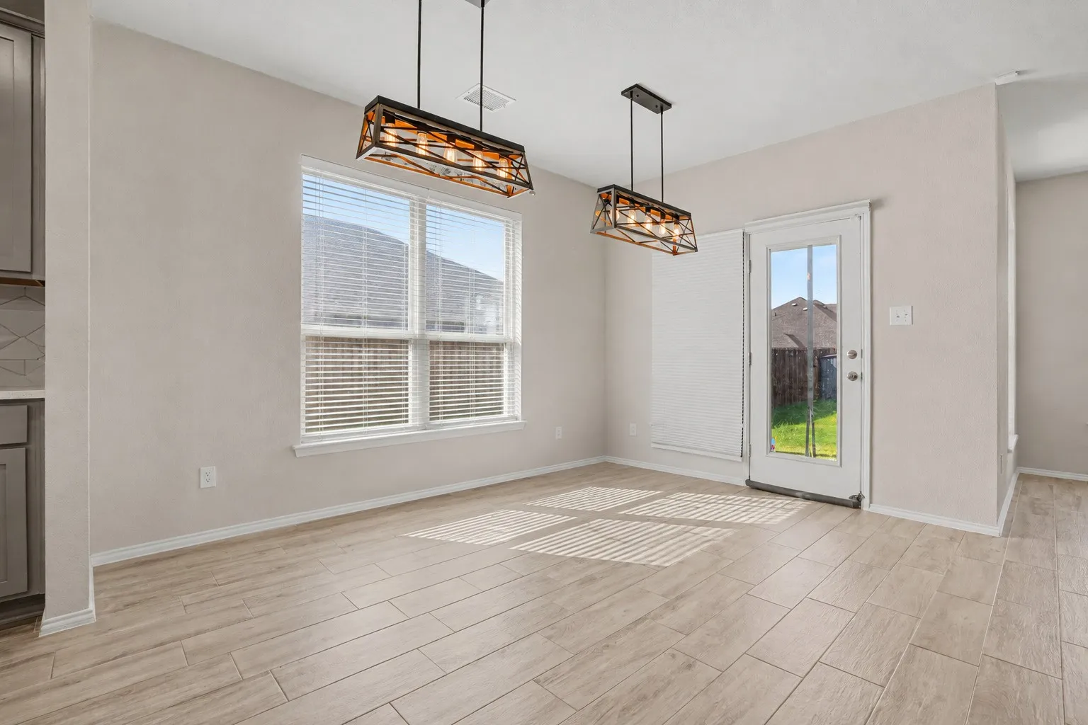 Wood-finish tile flooring throughout, featuring a double window with blinds and a glass-paneled door