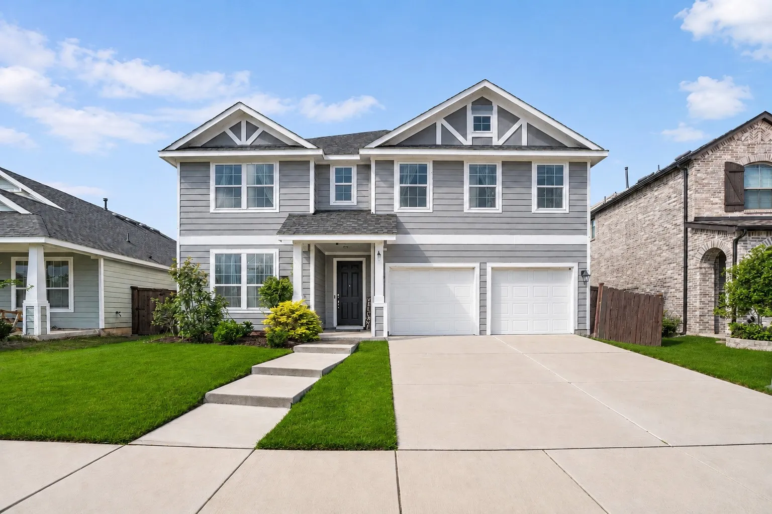 Two-story facade with gray siding, white trim, a covered front entry, and an attached two-car garage