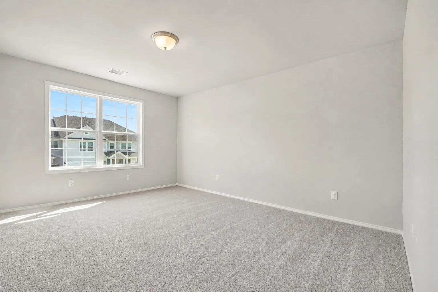 Expansive room featuring light gray carpeting and a large window with white trim