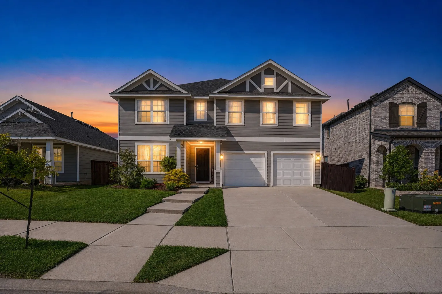 Two-story exterior with gray siding, a gabled roofline, and a two-car garage