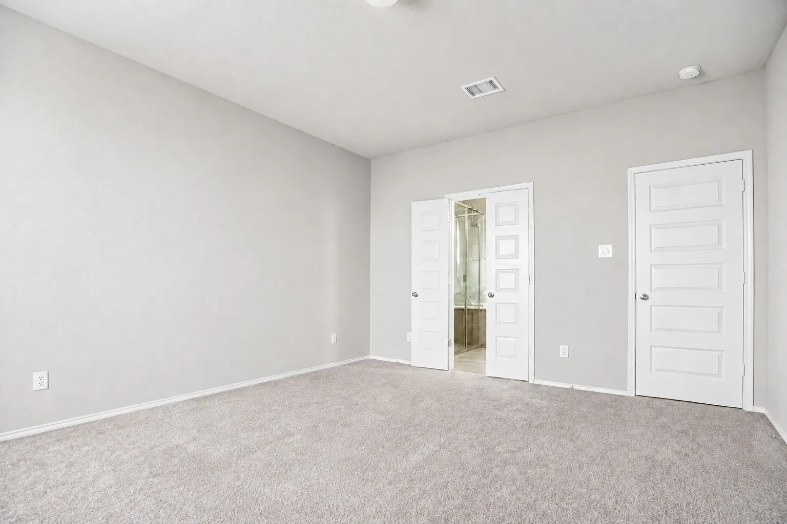 Neutral wall paint and carpeting, with a five-panel interior door and bifold doors revealing a bathroom with a tub and shower