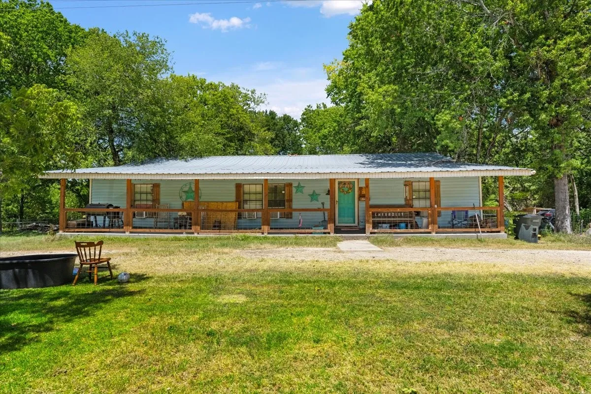 Light blue siding exterior with a metal roof and a full-length covered front porch featuring wood support posts
