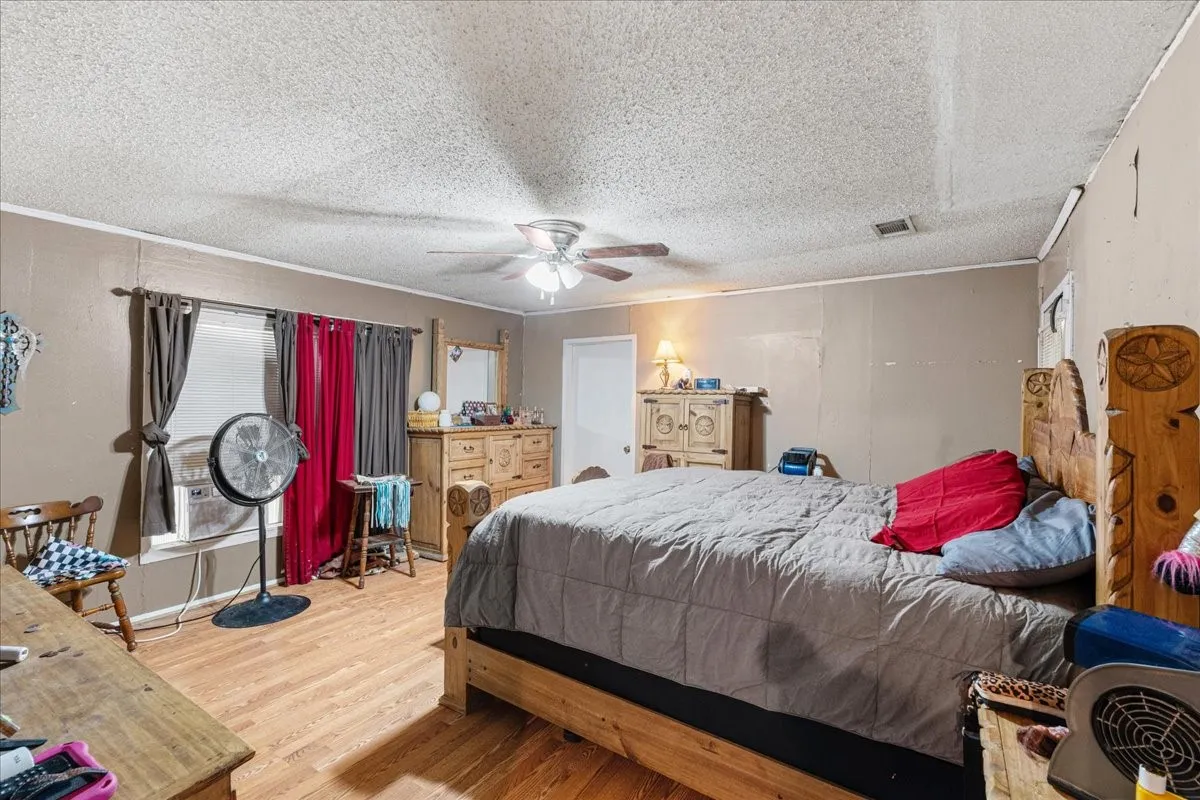 Wood-finish flooring, ceiling fan with integrated lighting, and a white interior door