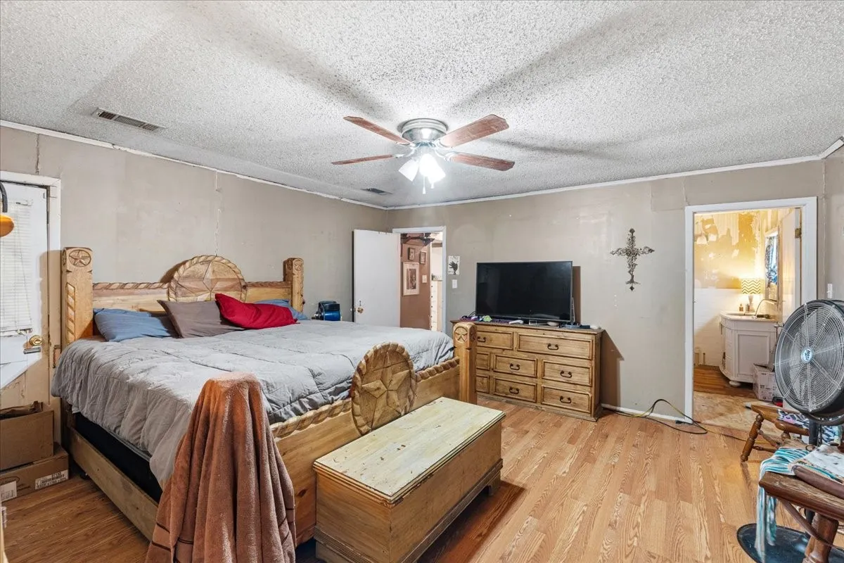Wood-finish flooring throughout, ceiling fan with integrated lighting, and a neutral wall color