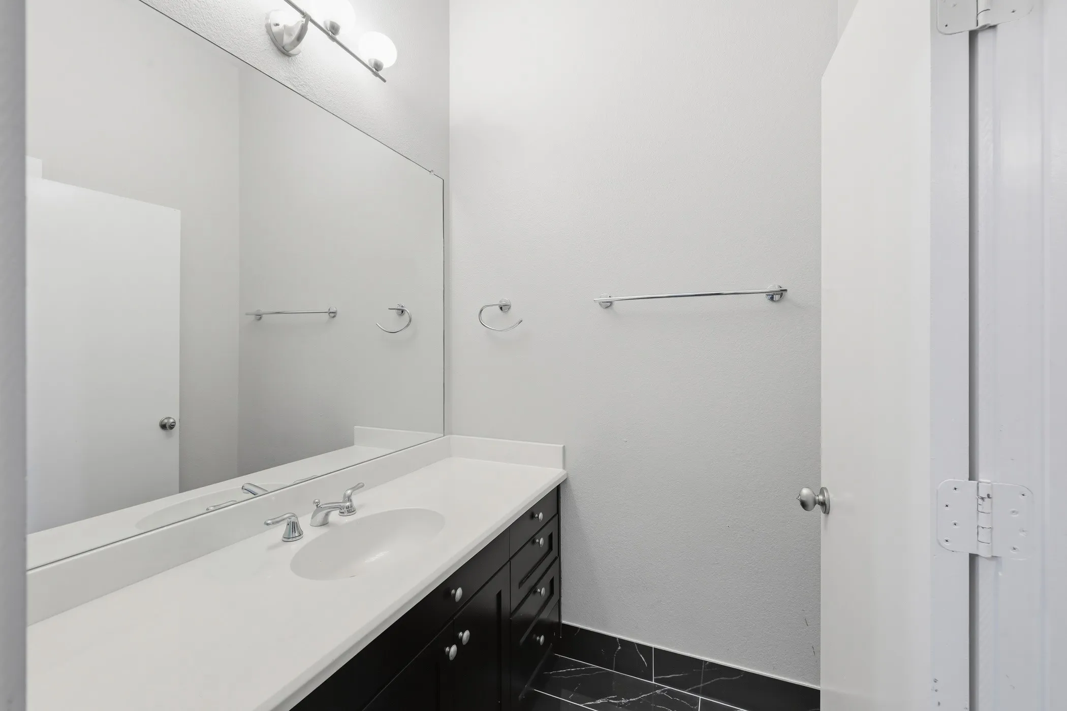 Dark wood-finish vanity with chrome hardware, white solid surface countertop, and integrated oval sink